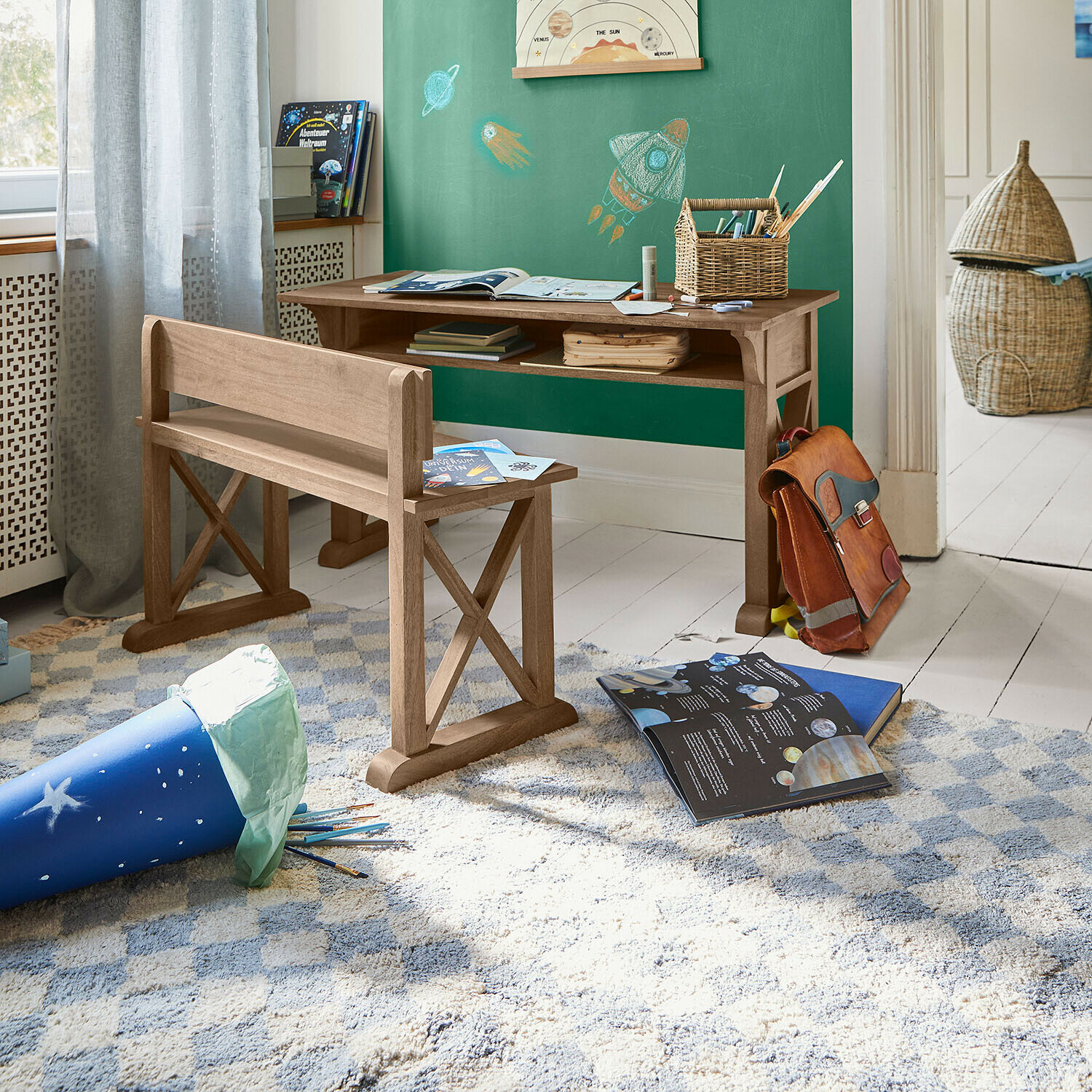 Schreibtisch und Bank aus Naturholz im Kinderzimmer mit Weltraummotiven an der grünen Wand