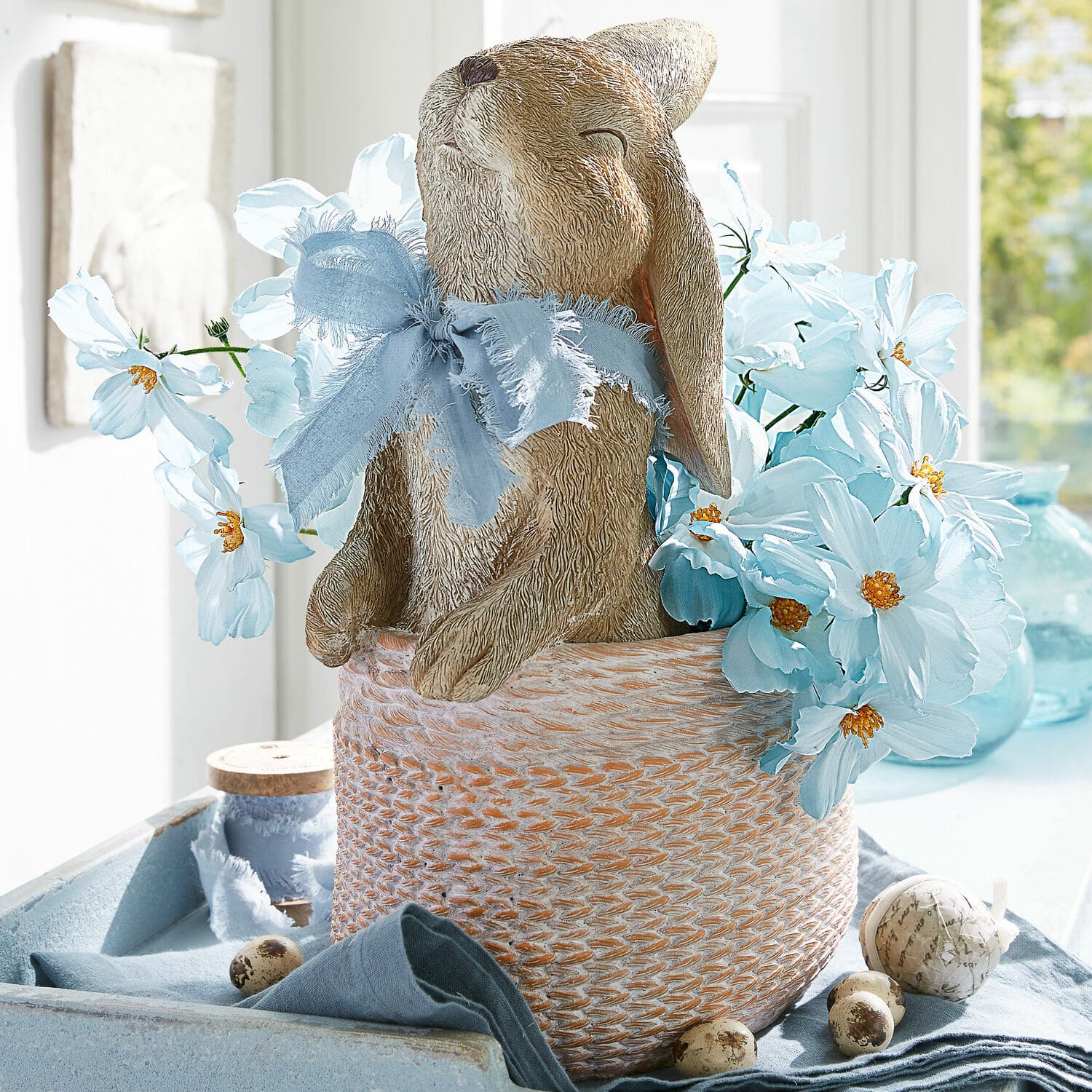 Übertopf Merisette Dekorativer Hase aus Material im Korb mit blauen Blumen und Schleife für Frühlingsdeko