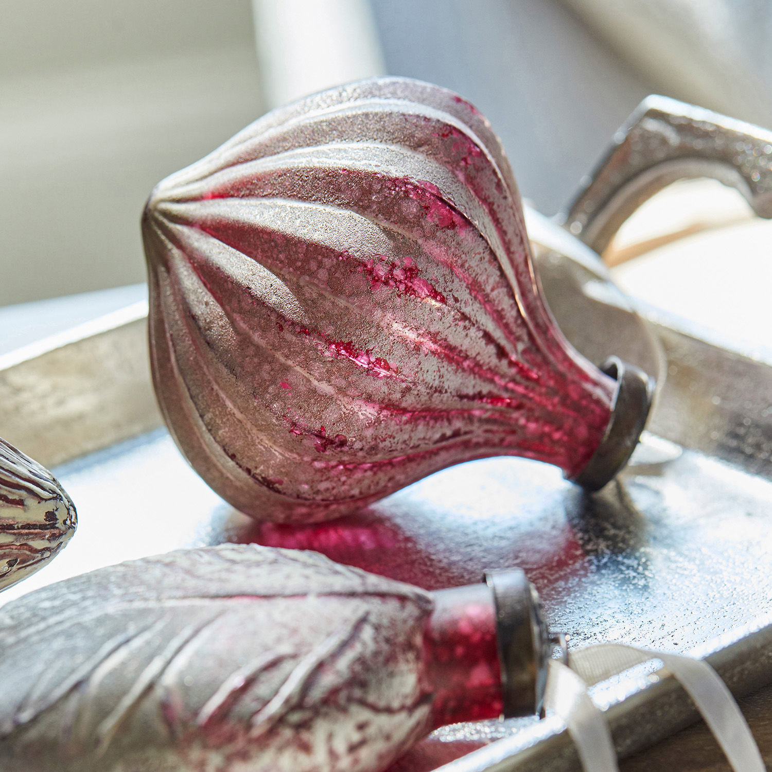 Weihnachtliche Dekoration aus rotem und silbernem Glas auf einem Metalltablett
