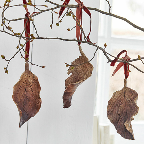 Dekorative braune Keramik-Blattanhänger an roten Bändern zum Hängen im Raum