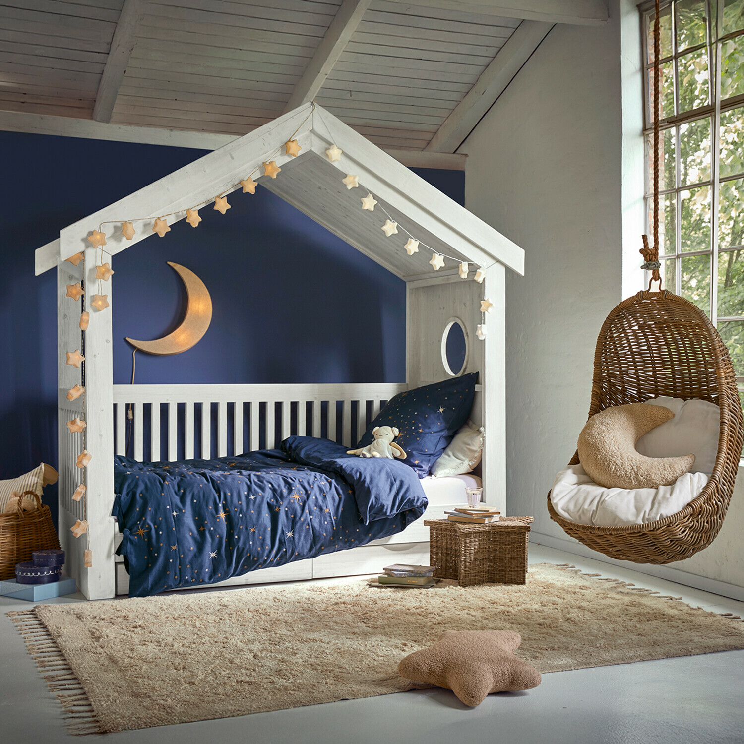 Teppich Avenagh Weißes Holzhaus-Bett mit dunkelblauer Sternenbettwäsche und hängendem Korbsessel im Kinderzimmer