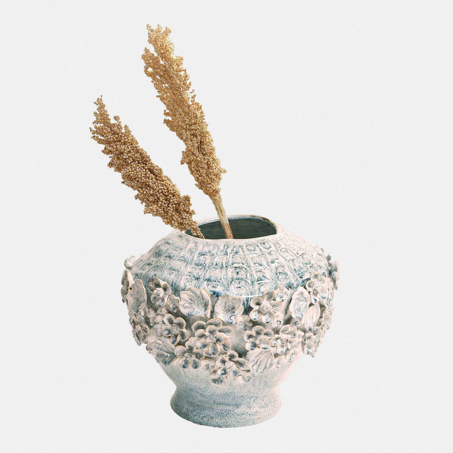 Keramikvase in Grau-Blau mit floralem Relief und getrockneten Ziergräsern im Inneren