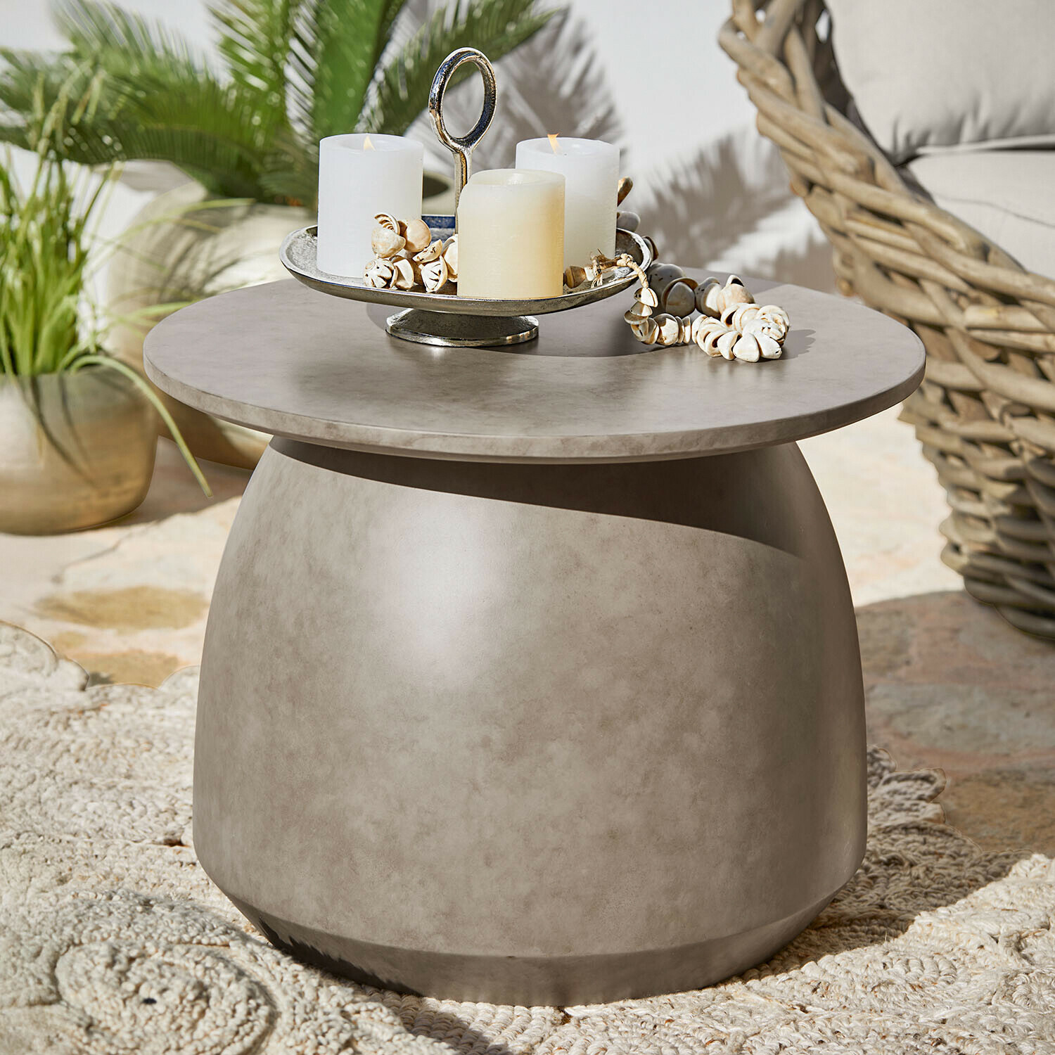 Runder Beistelltisch aus grauem Beton mit Kerzen und Muschel-Dekoration auf Terrasse