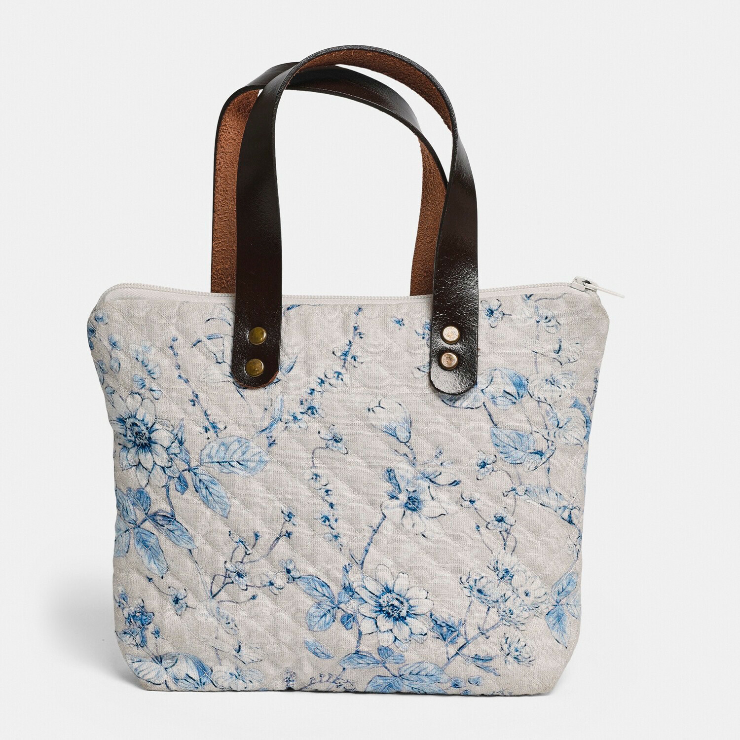 Beige gesteppte Tasche mit blauem Blumenmuster und schwarzen Ledergriffen, modisches Accessoire
