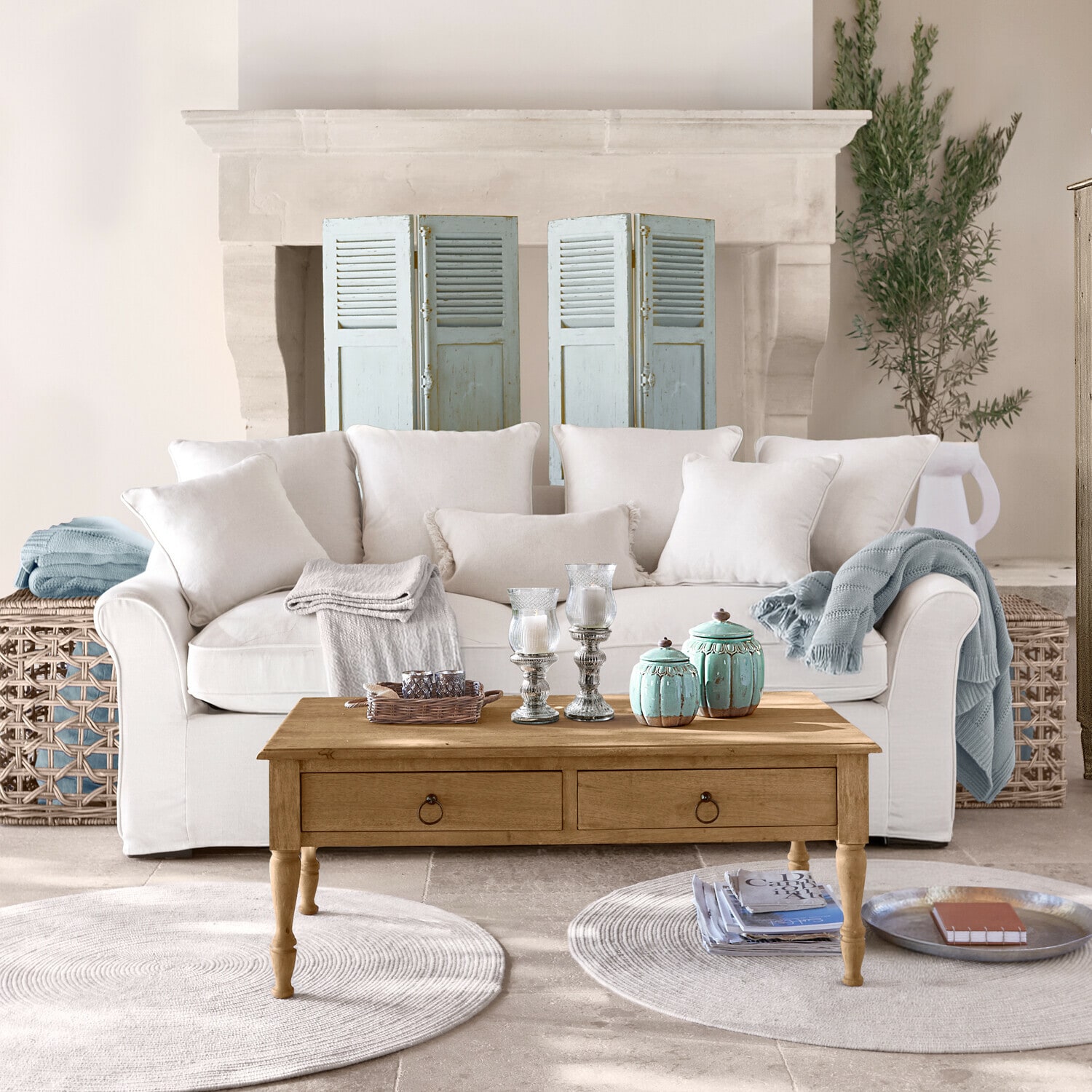 Beiges Sofa mit Kissen und Holzcouchtisch mit Dekorationen in hellem Wohnzimmer mit Teppichen