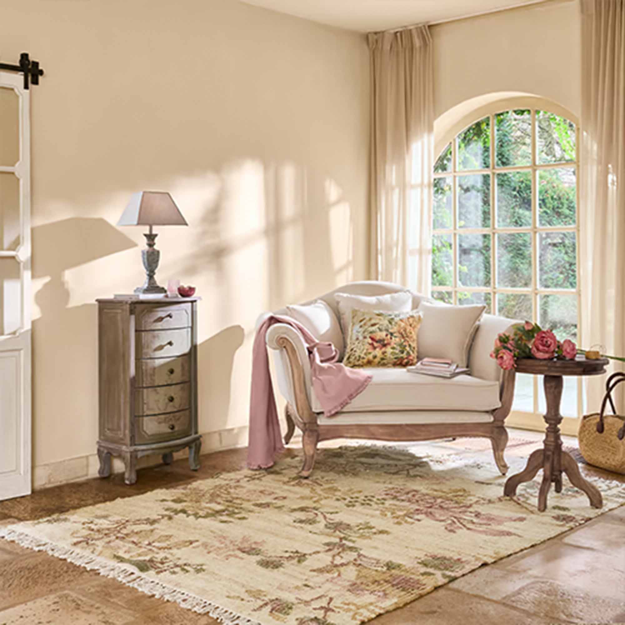 Gemütliches Wohnzimmer mit beigem Sofa, Holztisch und Lampe, helles Interieur mit großem Fenster