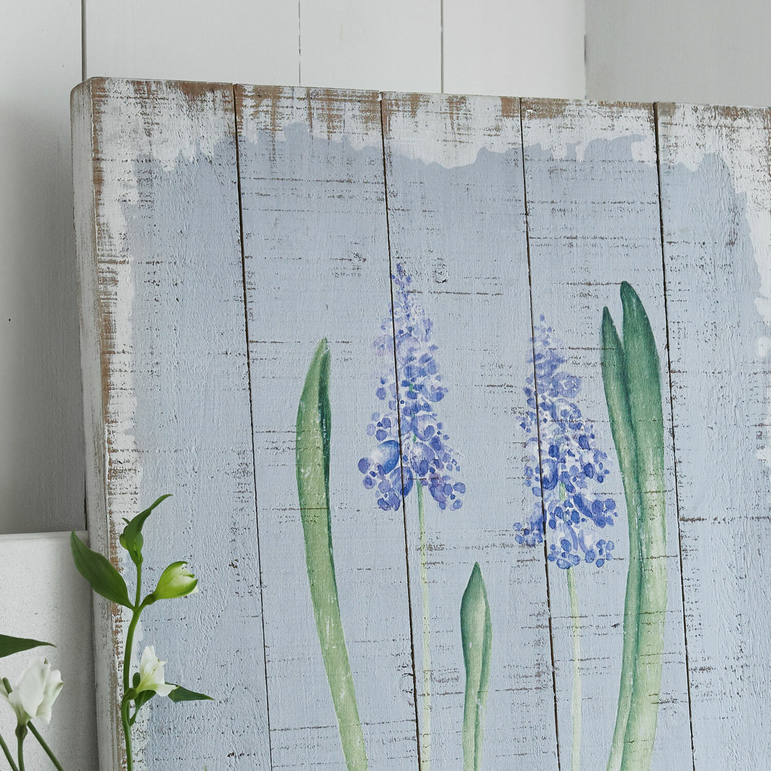 Holzbild mit Motiv violetter Blumen und grüner Blätter auf hellblauem Hintergrund