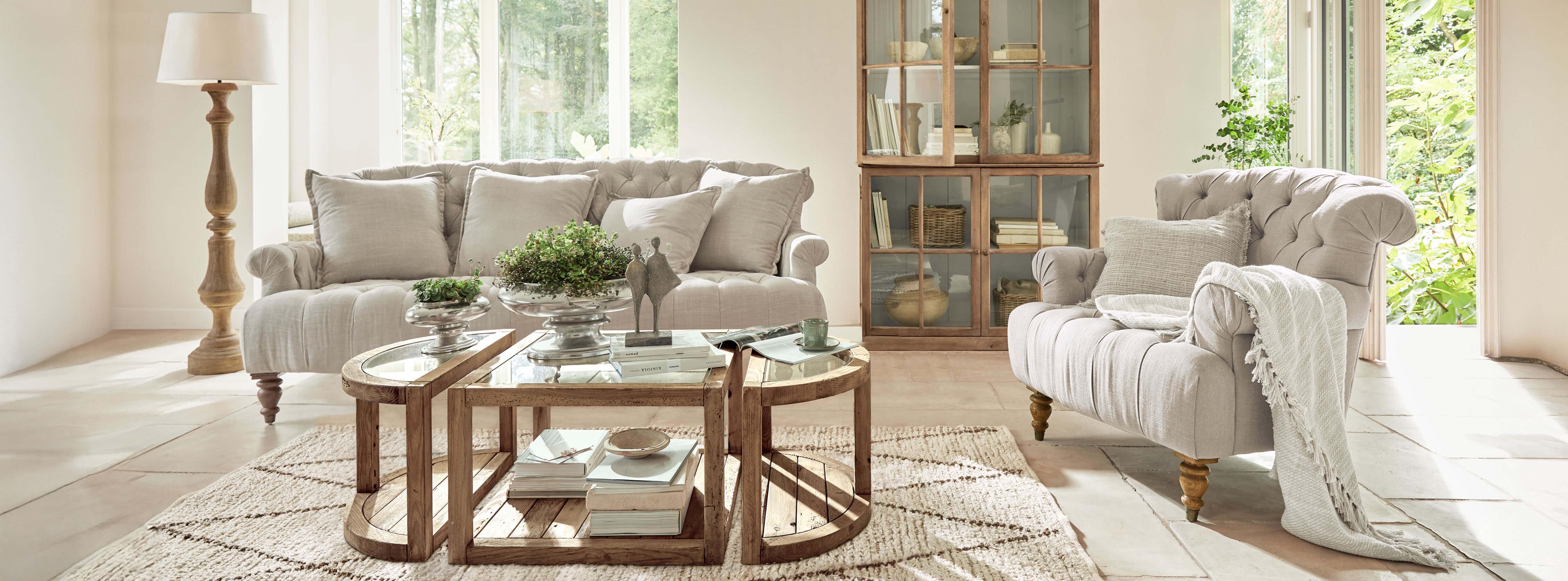 Gemütliches Wohnzimmer mit beigem Stoffsofa, Sessel, Holzcouchtisch und Stehlampe