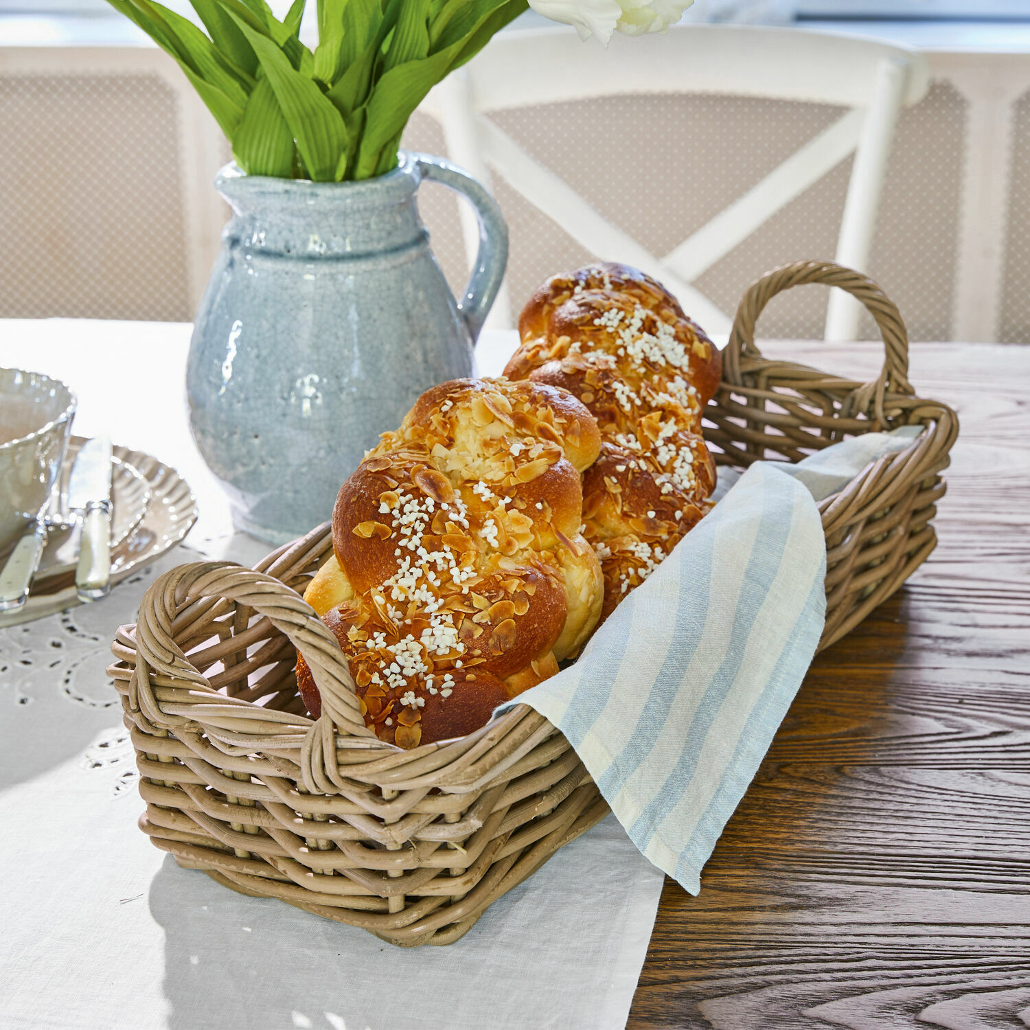 Korb Balmis Wickerkorb mit zwei Griffen, gefüllt mit Hefezopf und Leinenstoff auf Holztisch