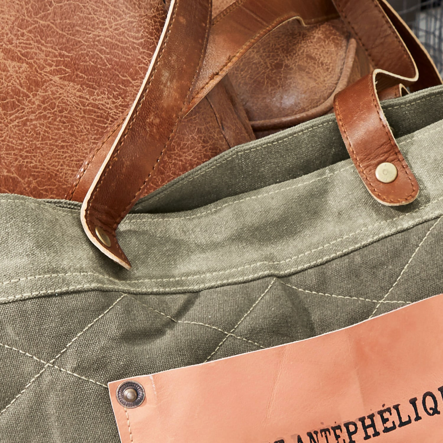 Tasche aus grünem Canvas mit braunen Ledergriffen und hellrosa Lederpatch