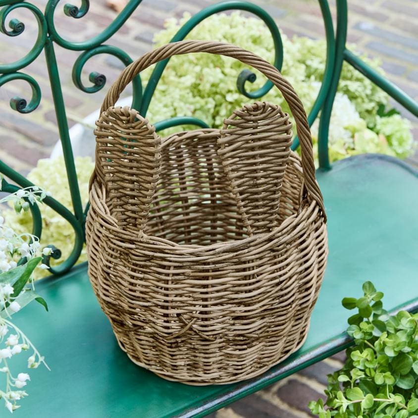 Naturfarbener Weidenkorb mit Griffen auf grünem Gartenbank, dekorativer Korb für draußen