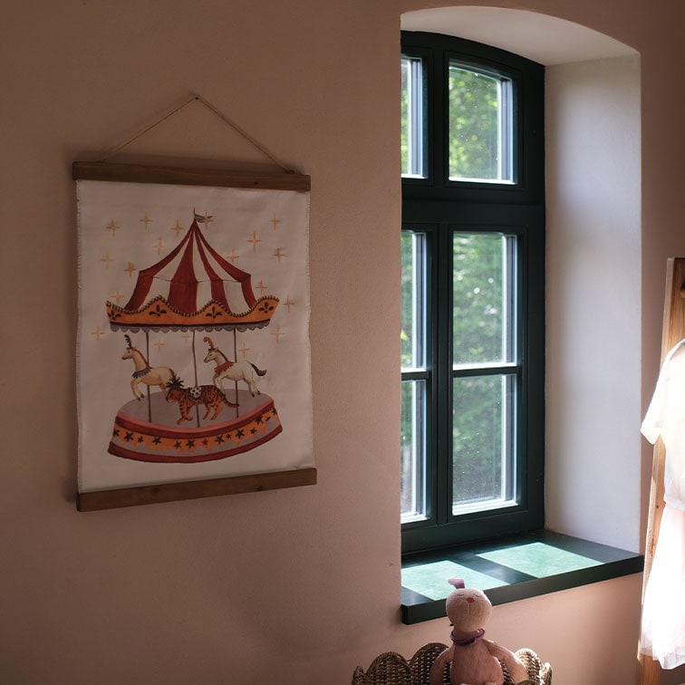 Dekoratives Wandbild aus Stoff mit Karussell und Tieren in einem warmen Kinderzimmer