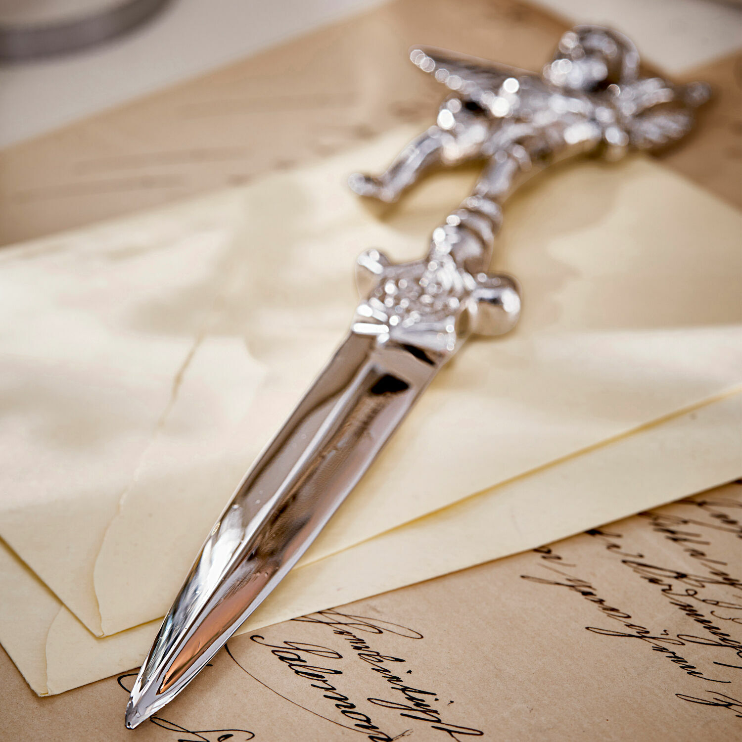 Silberner Brieföffner aus Metall mit verziertem Griff auf alten Briefen und Papier