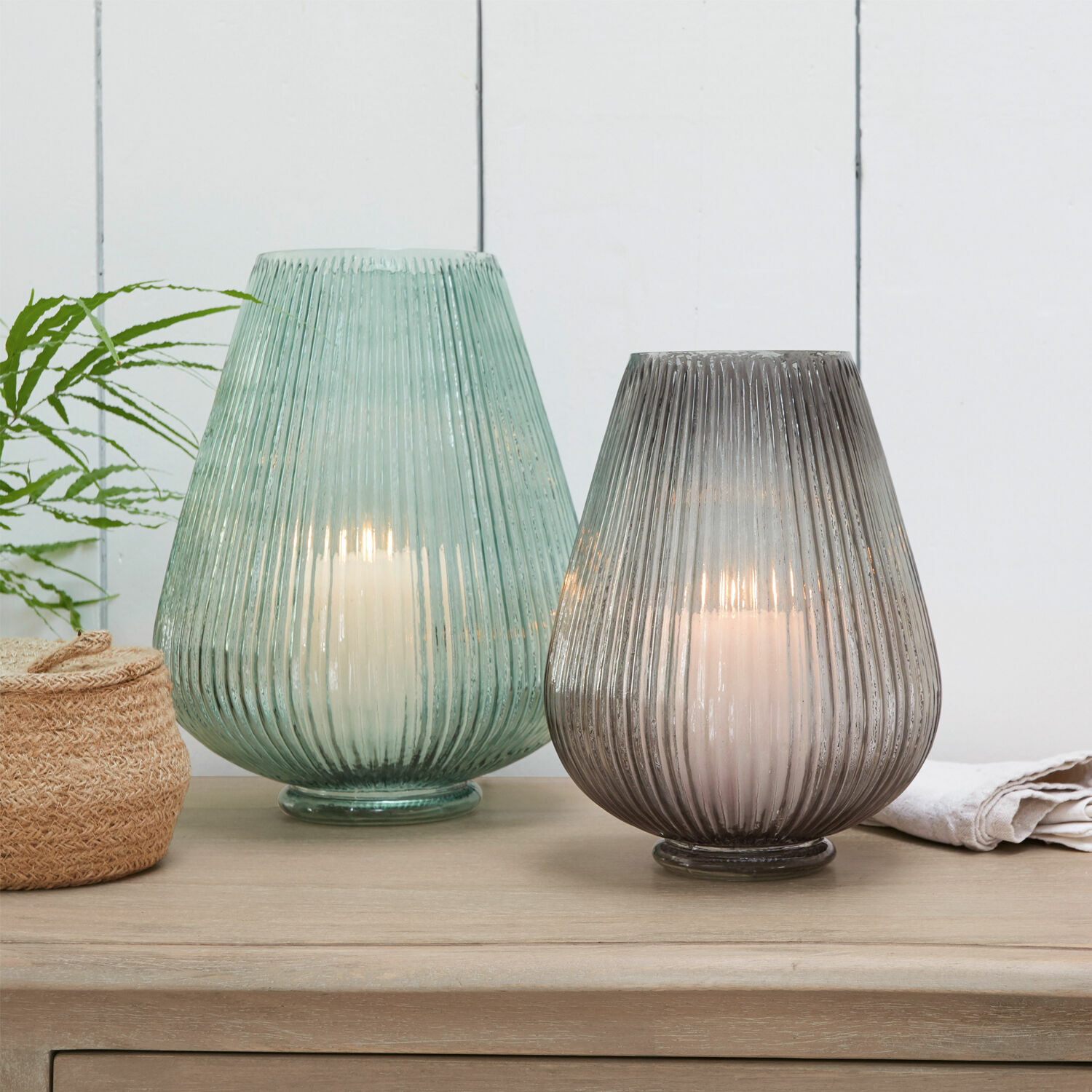 Vase 2er Set Fenis Zwei Glaslaternen in Grün und Grau mit weißen Kerzen auf hellem Holztisch