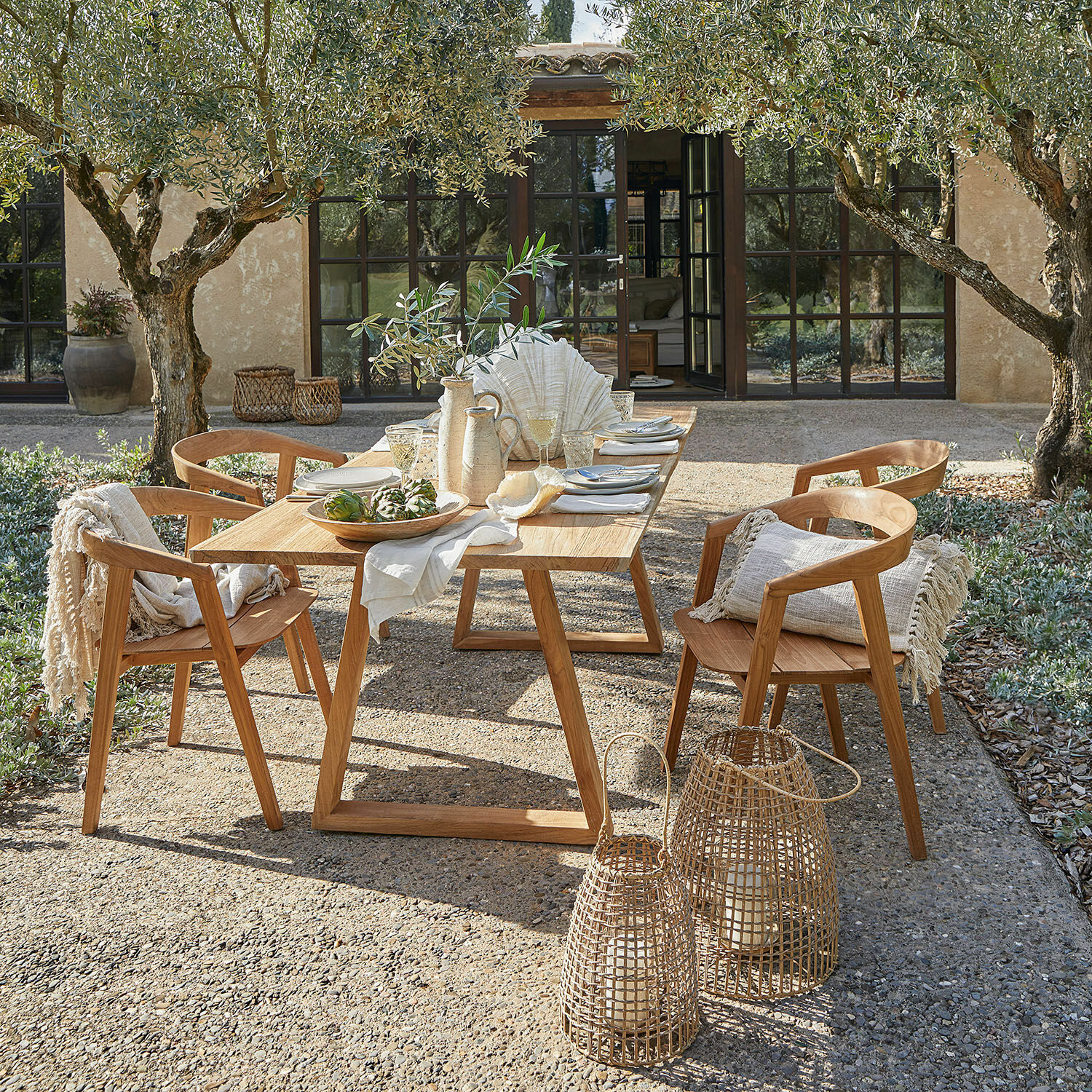 Gartenmöbel-Set aus natürlichem Teakholz mit Dekorationen und Laternen auf sonniger Terrasse