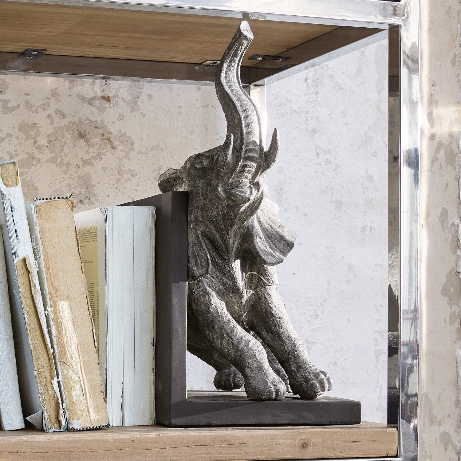 Buchstütze Elefant aus grauem Stein auf Holzregal als dekoratives Wohnaccessoire