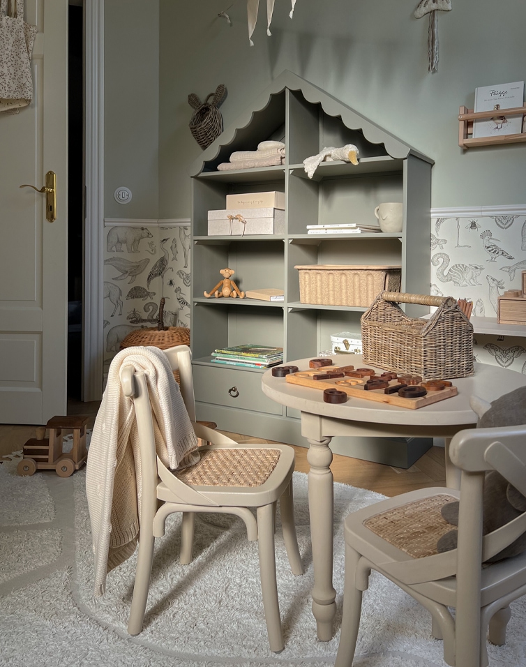 Kinderzimmer mit grauem Holzregal in Hausform und beigen Stühlen mit geflochtenem Sitz