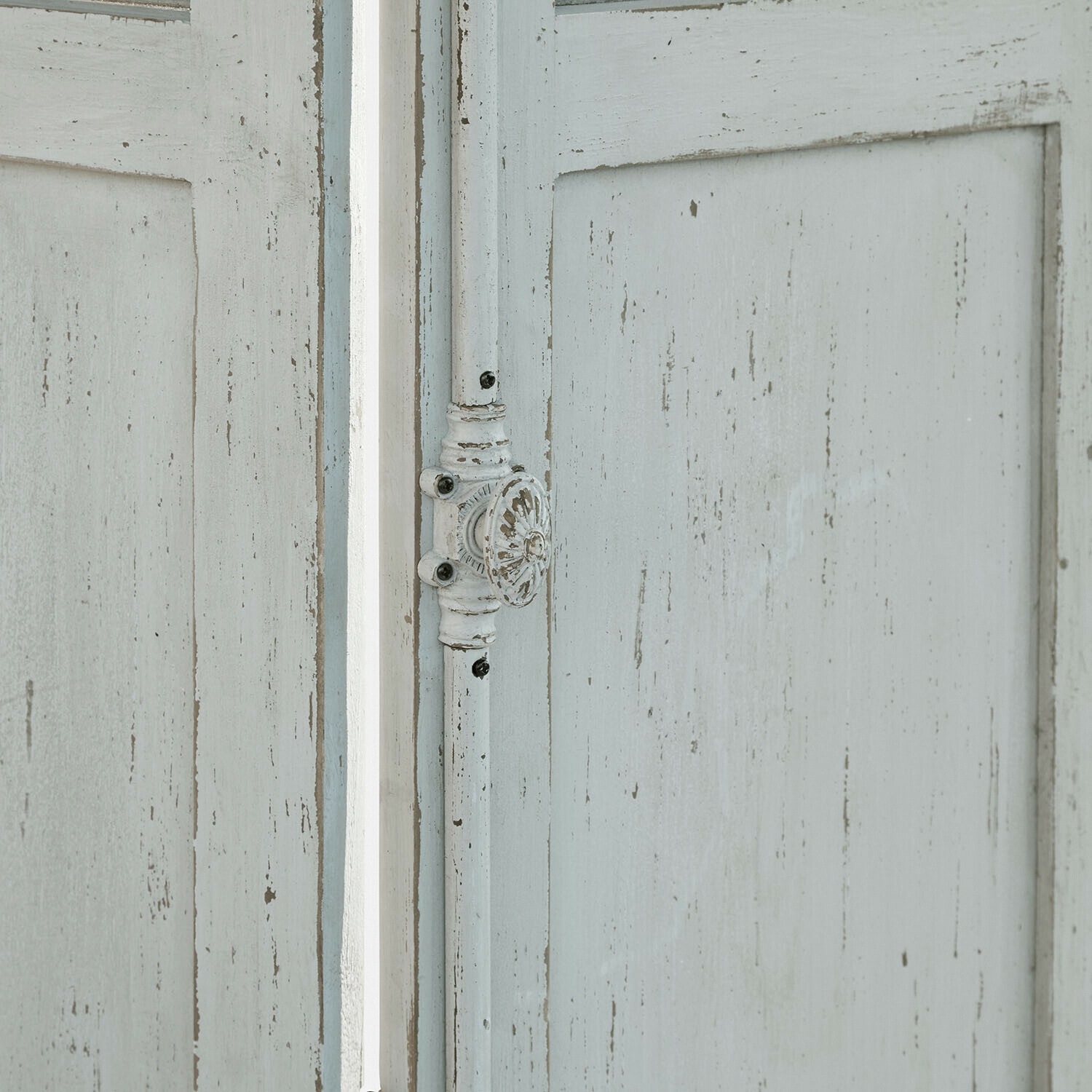 Alte weiße Holztür mit abblätternder Farbe und rundem Metallgriff im Vintage-Stil