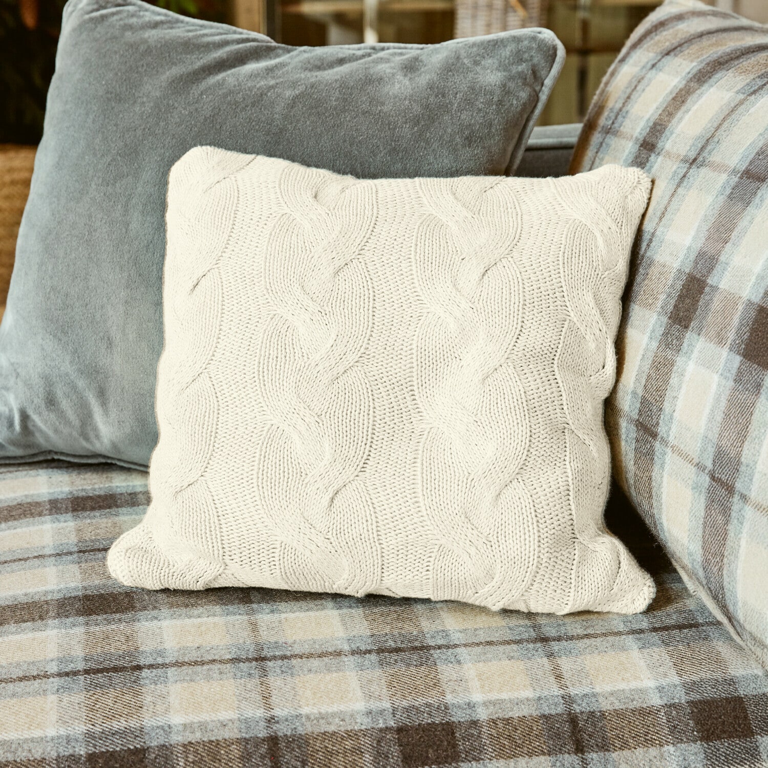 Kissenhülle Arnhem Beige Strickkissen mit Zopfmuster auf kariertem Sofa, gemütliche Wohnraumdekoration