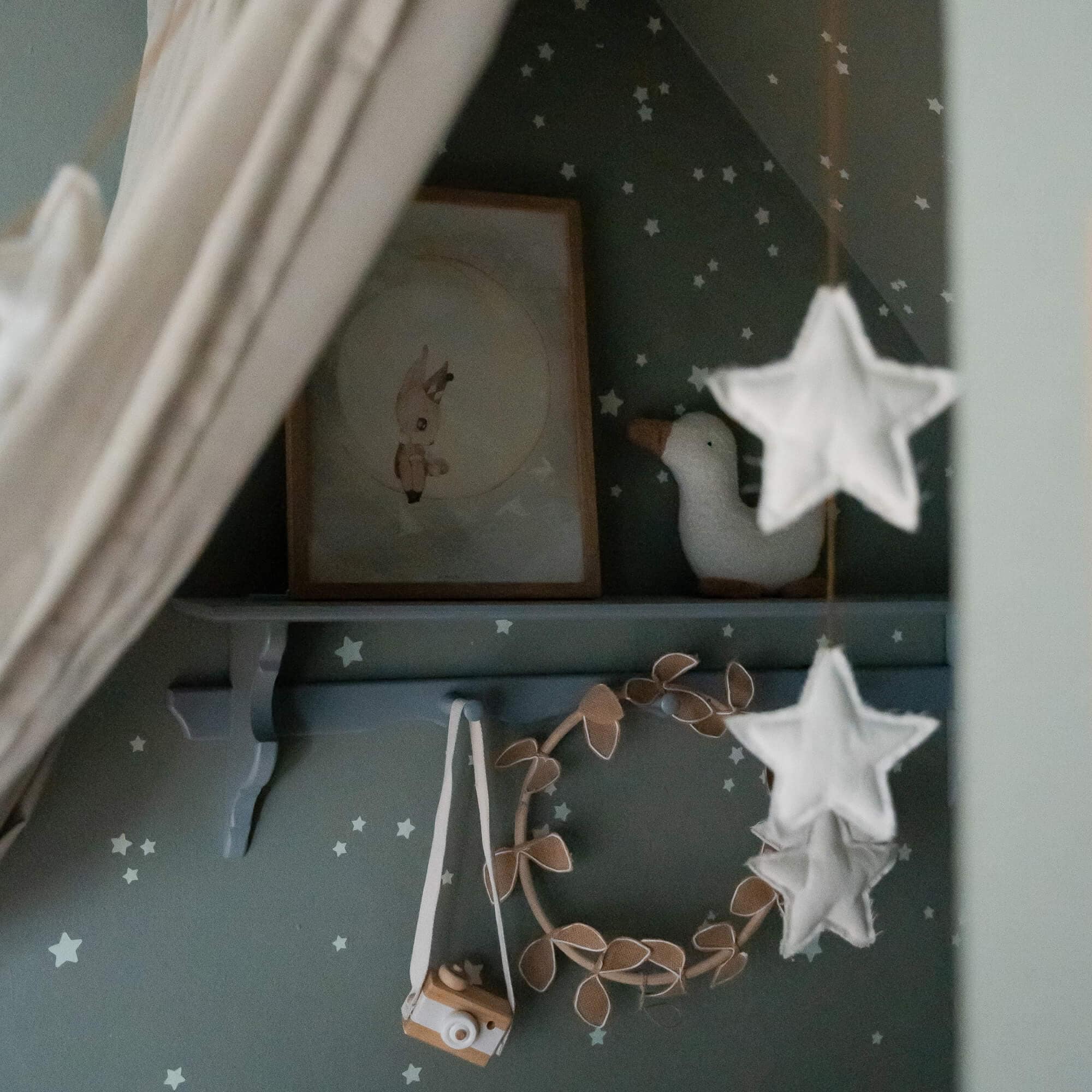 Kinderzimmerdeko mit weißer Plüschente, Holz-Kamera und Sternen an grüner Wand
