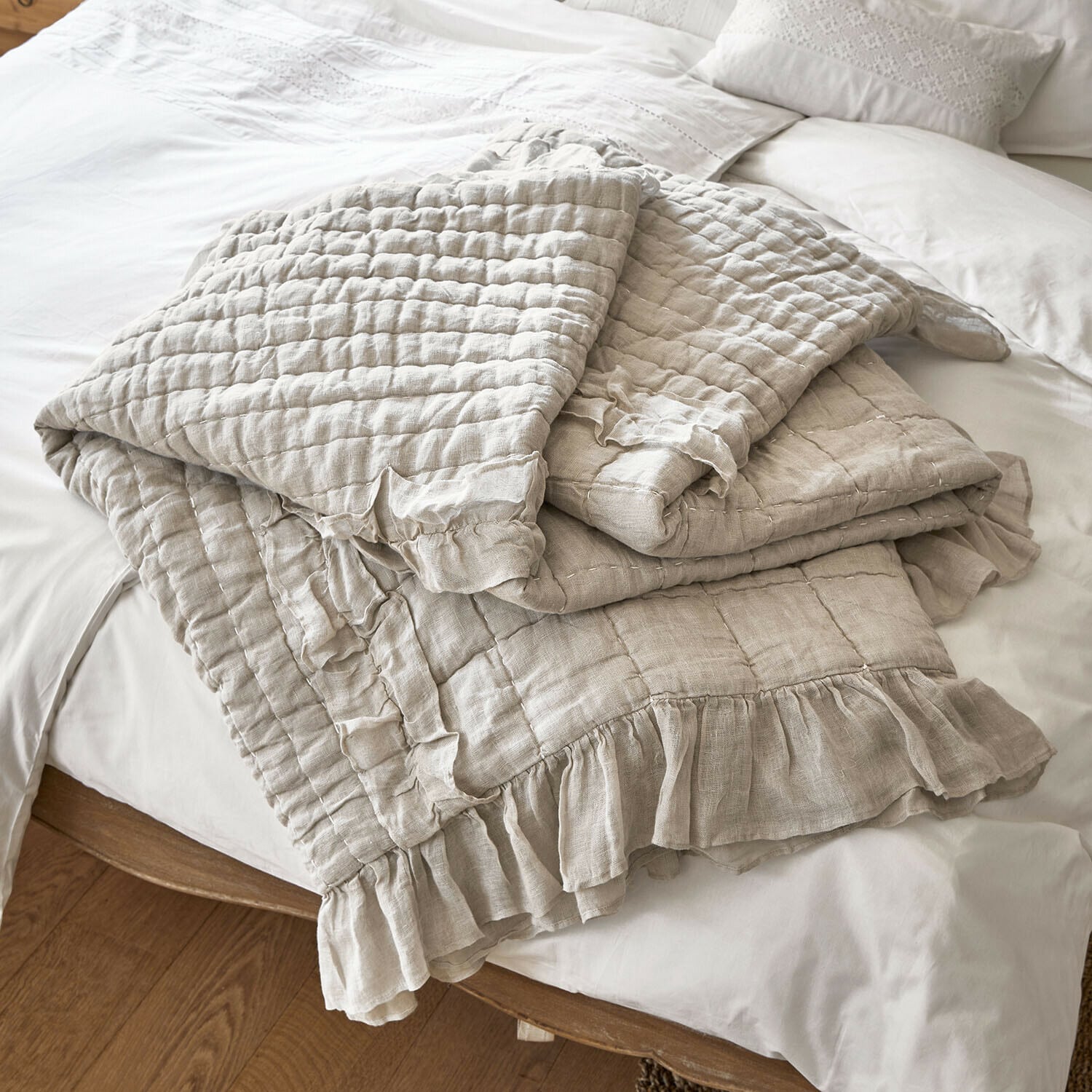 Beige gesteppte Leinenbettdecke mit Rüschen auf weißem Bett, weiche und dekorative Bettwäsche
