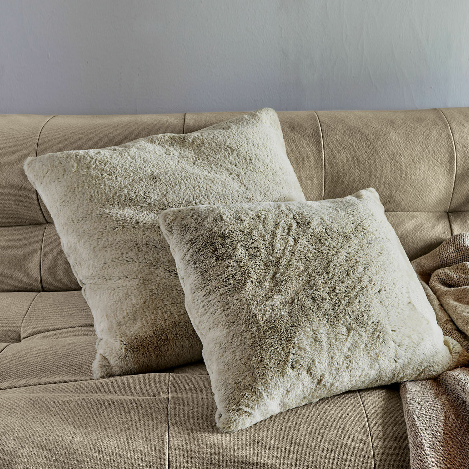 Kissenhülle 2er Set Newman Weiche beige Kissen aus flauschigem Material auf hellbraunem Sofa im Wohnzimmer