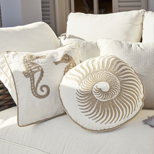 Dekorative Kissen mit Meeresmotiven auf cremefarbenem Stoff auf Sofa, maritimer Stil