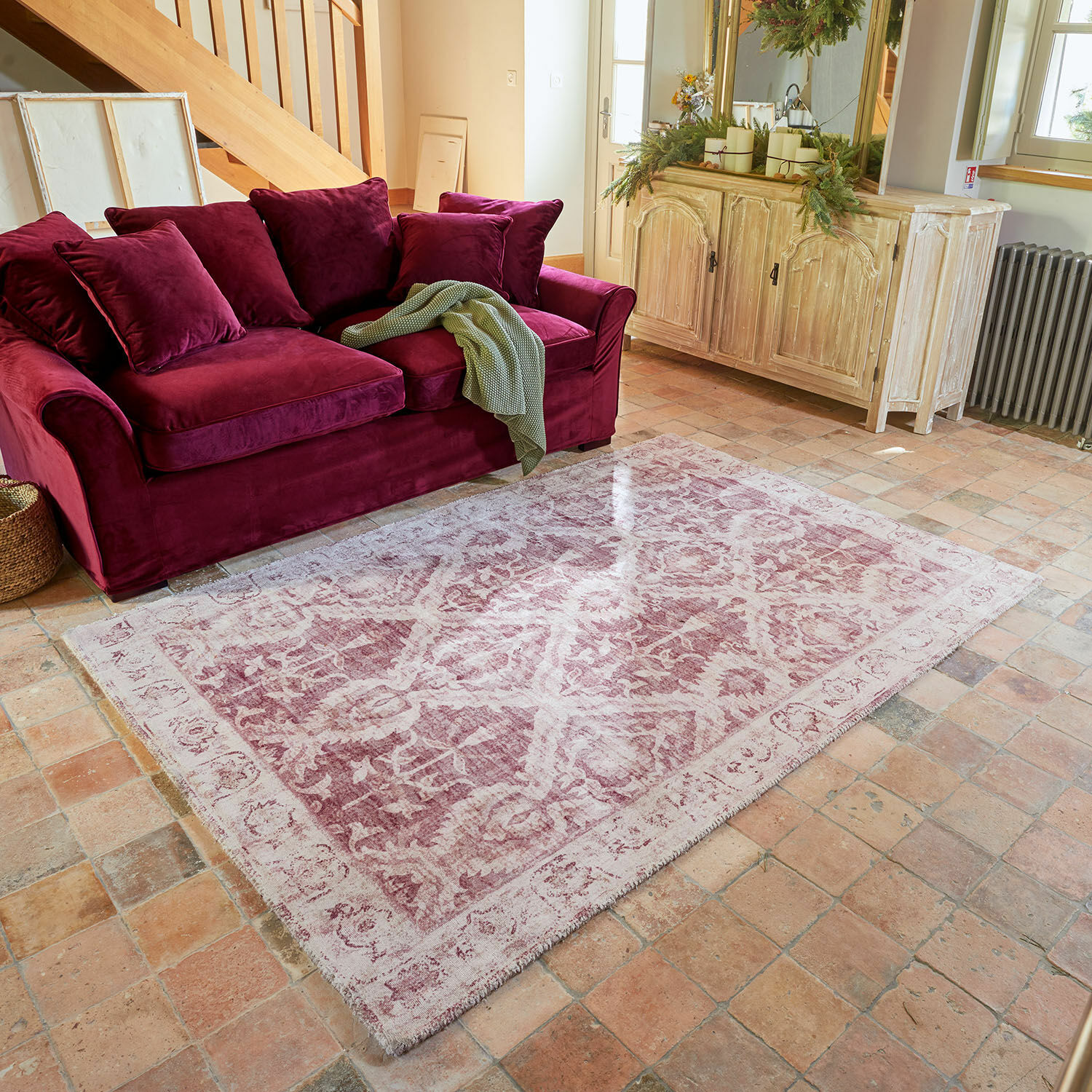 Teppich Mirellis Rotes Samtsofa mit Kissen und grünem Plaid auf Vintage-Teppich in gemütlichem Wohnzimmer