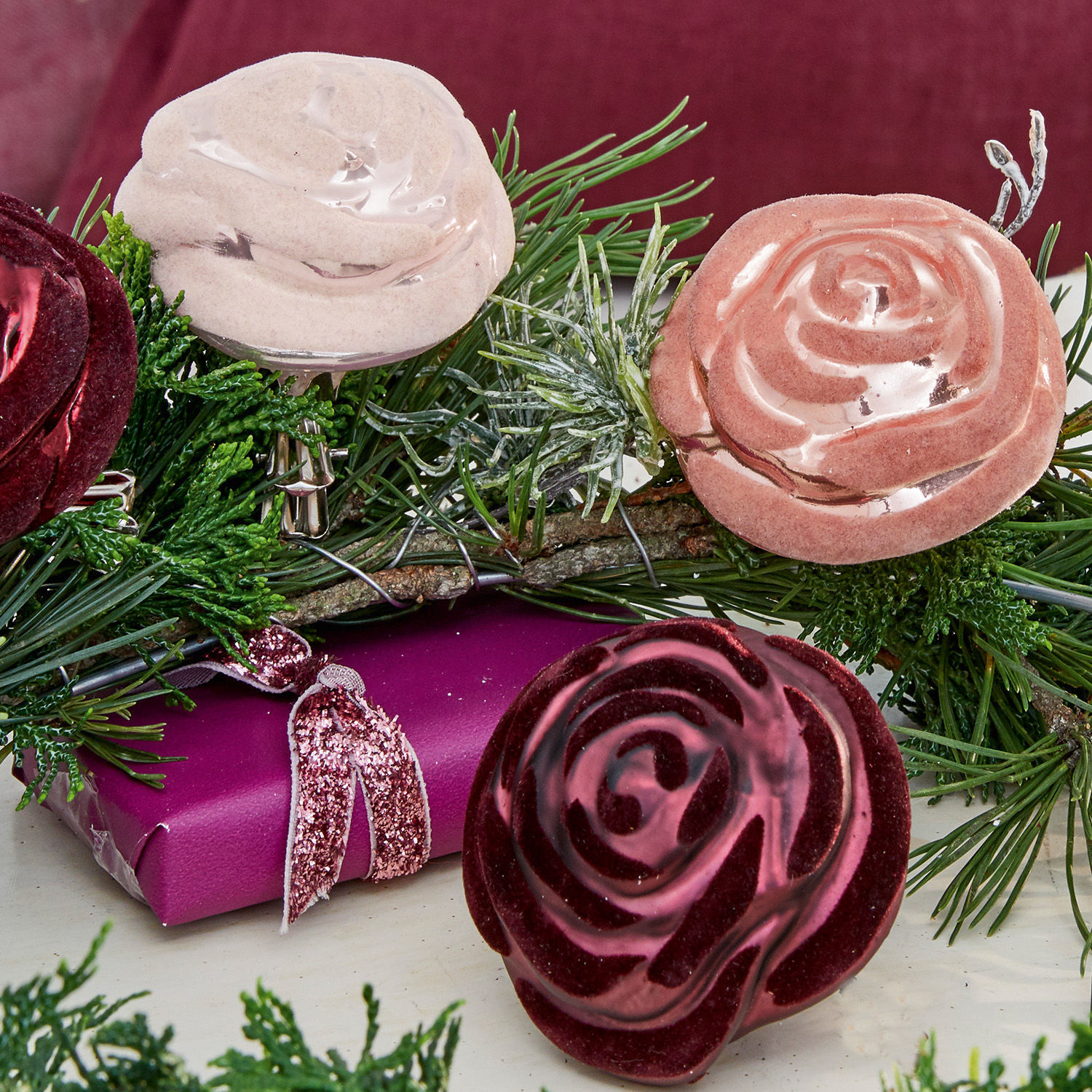 Dekorative Rosenklammern in Bordeaux, Rosa und Beige mit grünen Zweigen als Weihnachtsdeko