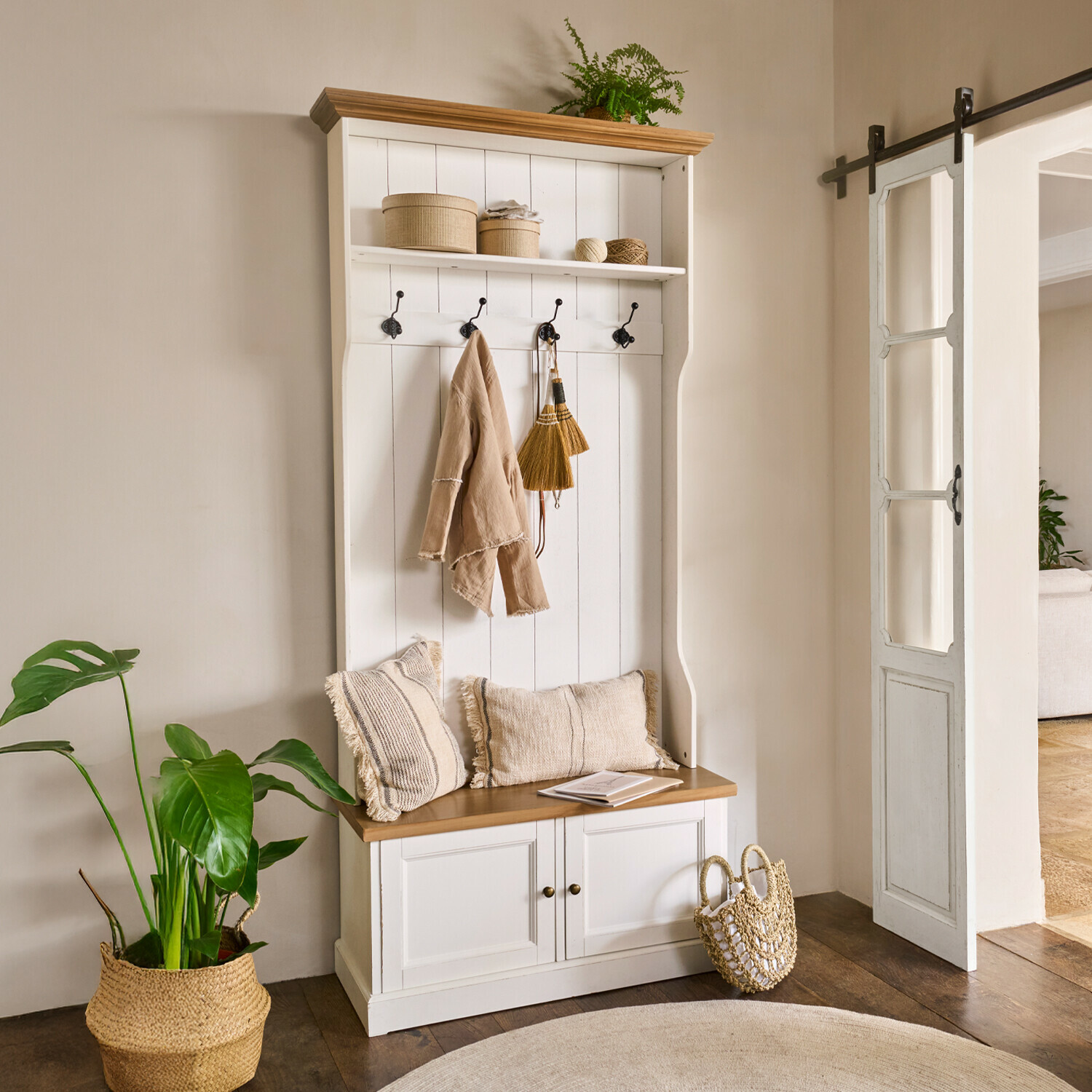 Garderobe Colchester Weiße Holzgarderobe mit Sitzbank, Haken, beigen Kissen und natürlichen Dekorationen im Flur