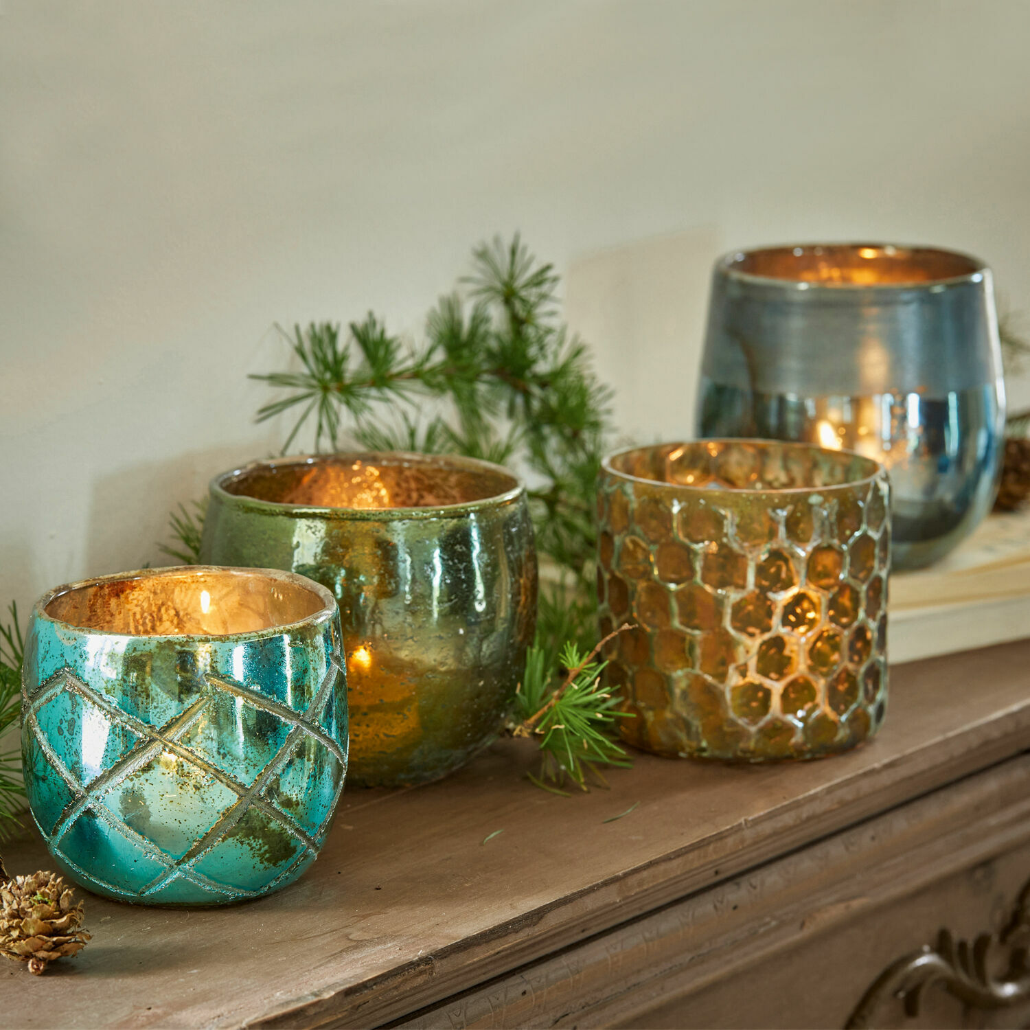 Teelichthalter 4er Set Marine Vier bunte Glas-Teelichthalter in Türkis, Grün und Gold auf einem Holzbrett arrangiert