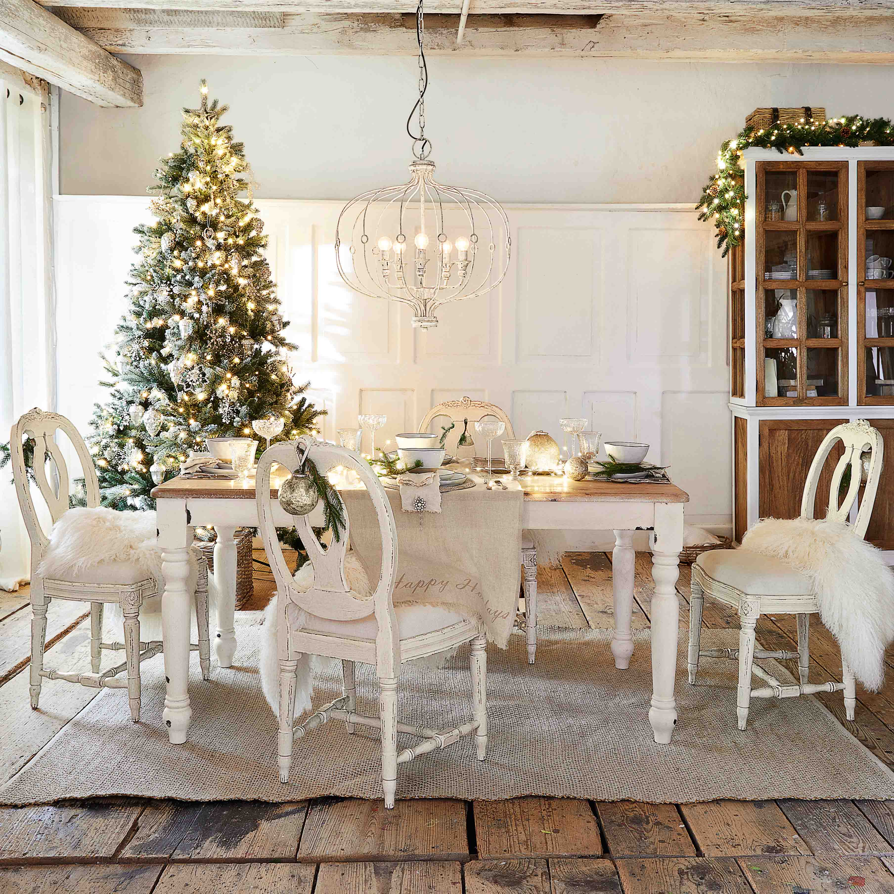 Rustikaler Essbereich mit weißem Holztisch und Stühlen, weihnachtlich dekoriert mit Baum und Lampe