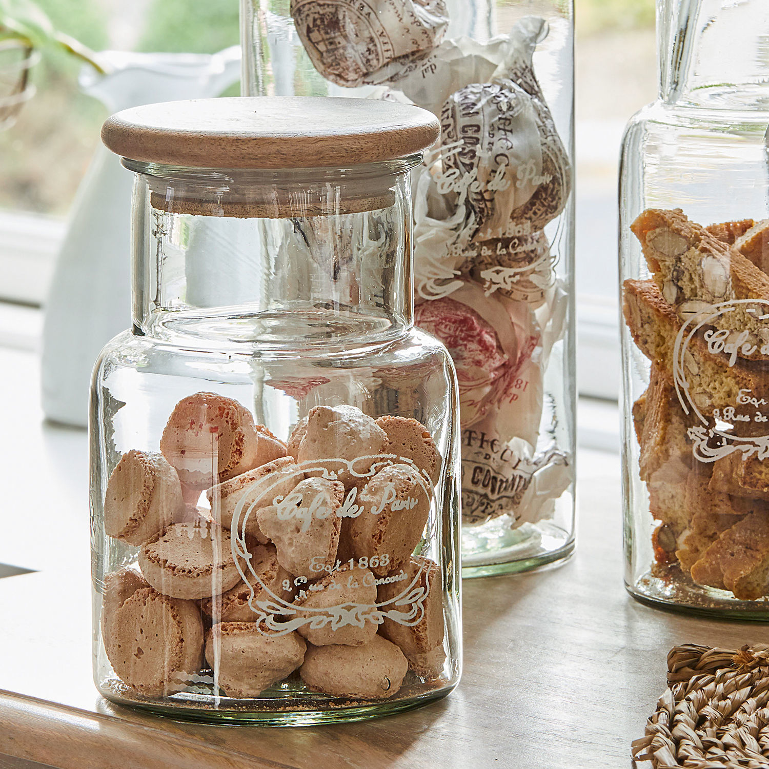 Glasbehälter mit Holzdeckel gefüllt mit französischen Keksen auf Küchenarbeitsplatte