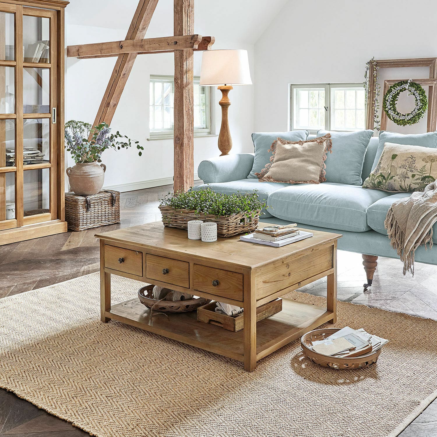 Holz-Couchtisch mit Schubladen auf Naturteppich in hellem Wohnzimmer mit hellblauem Sofa