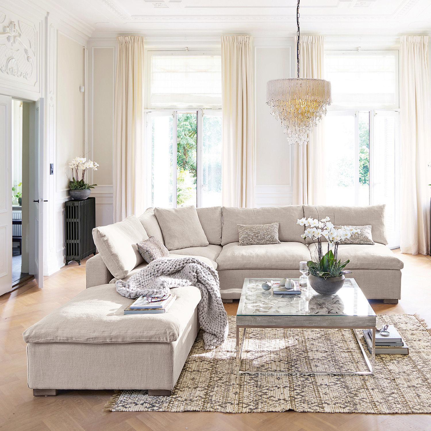 Beige Ecksofa aus Stoff im hellen Wohnzimmer mit dekorativem Teppich und Glastisch