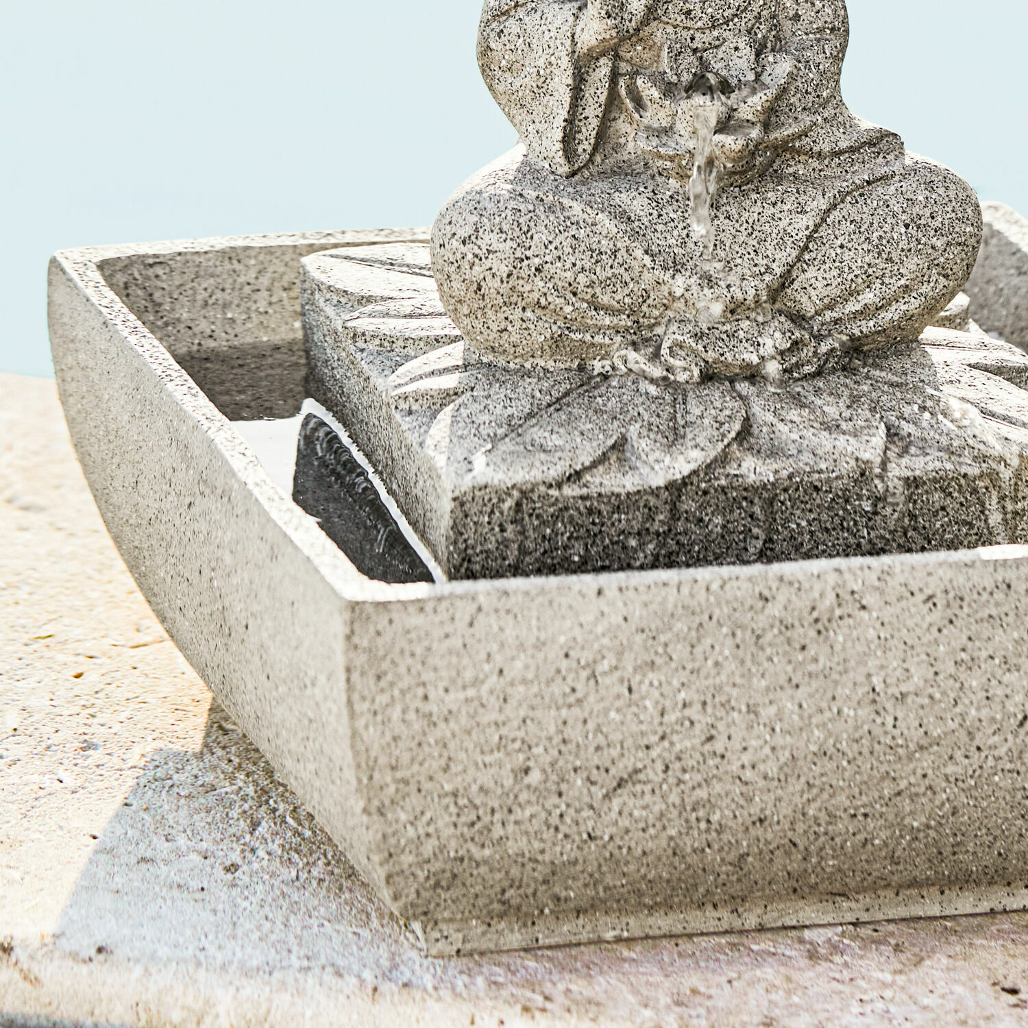 Dekorativer Springbrunnen aus grauem Stein mit Blumenmotiv und fließendem Wasser