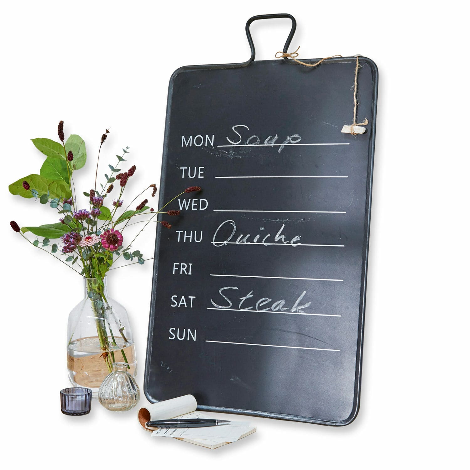 Wöchentliche Menütafel aus schwarzem Metall mit Kreideschrift und Blumen in Vase daneben