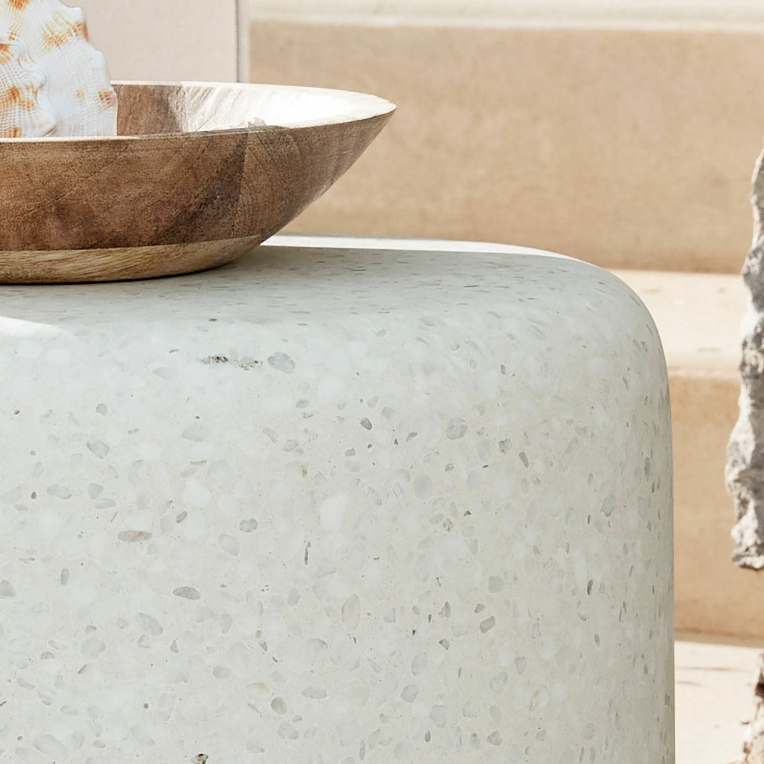 Tischplatte aus weißem Terrazzo mit abgerundeten Kanten und dekorativer Holzschale