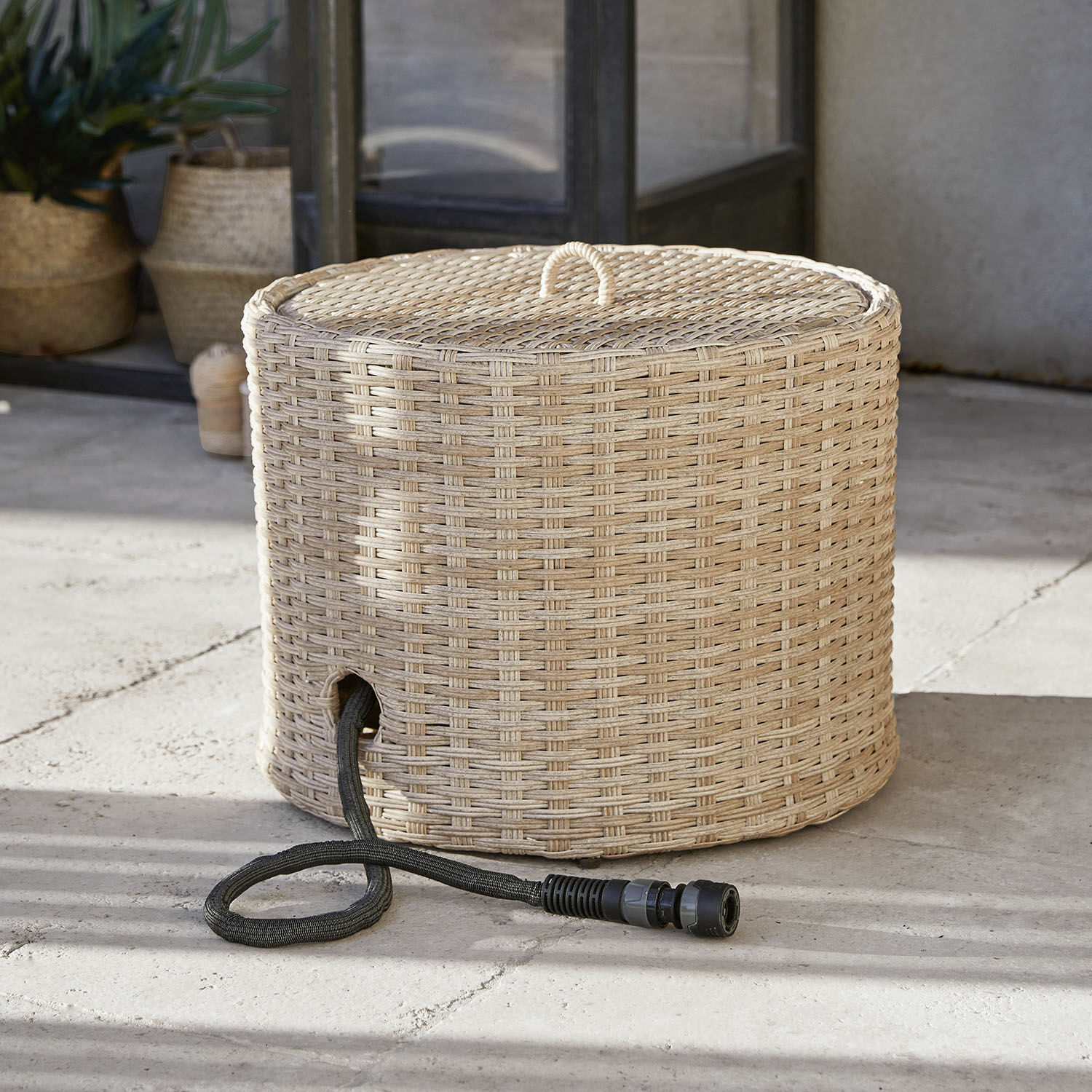 Runder Korb aus natürlichem Rattan mit Öffnung für schwarzen Gartenschlauch