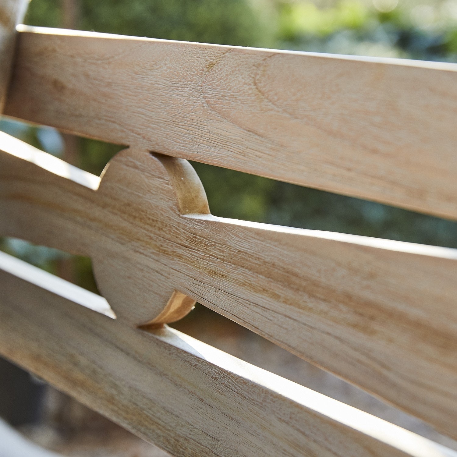 Detail eines hellen Holzmöbels mit dekorativem Ausschnitt und natürlicher Holzstruktur im Freien