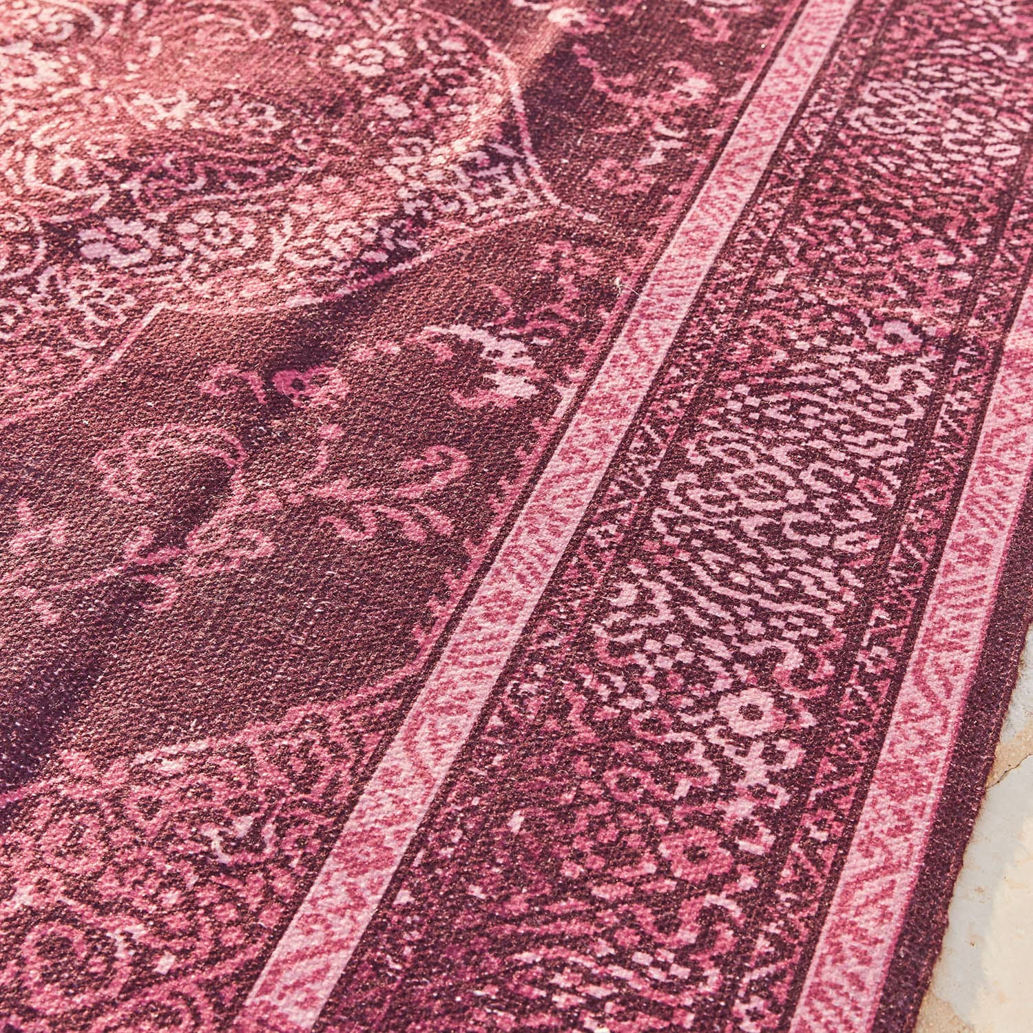 Orientalisch gemusterter Teppich in Rosa- und Bordeauxtönen aus Textilmaterial, Bodendekor