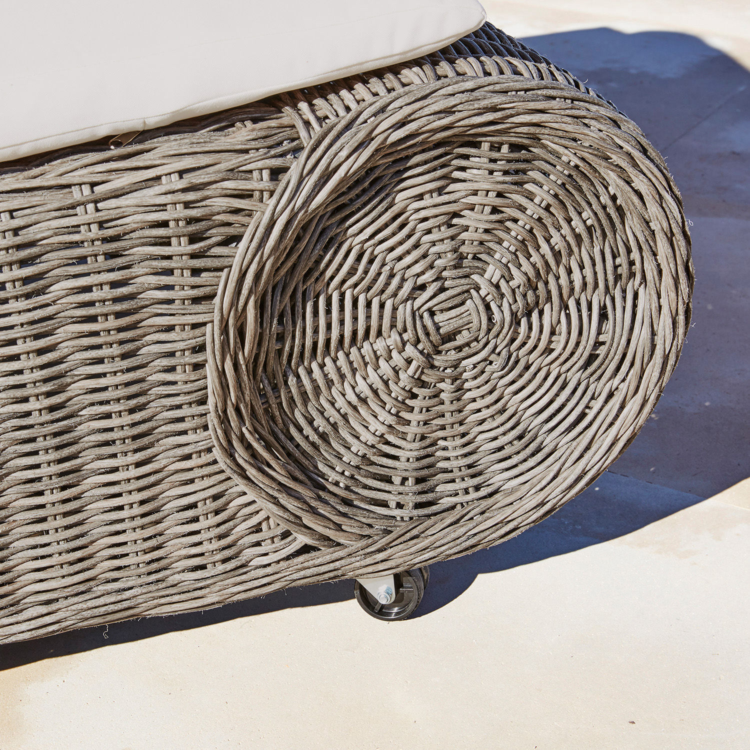 Nahaufnahme eines grauen Rattanmöbels mit Rollen, Outdoor-Gartenmöbel