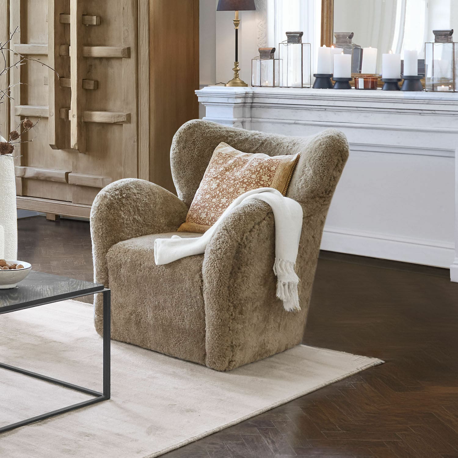 Sessel Ambrécourt Beiger Sessel aus weichem Material mit Kissen und weißer Decke im eleganten Wohnzimmer