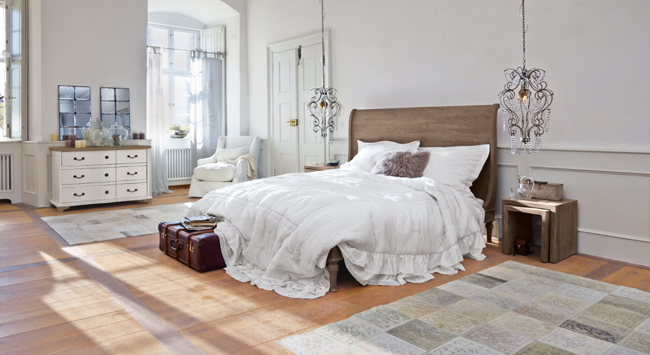 Moderne französische Schlafzimmerwelt mit Holzbett und weißer Bettwäsche auf hellem Holzboden mit Teppich