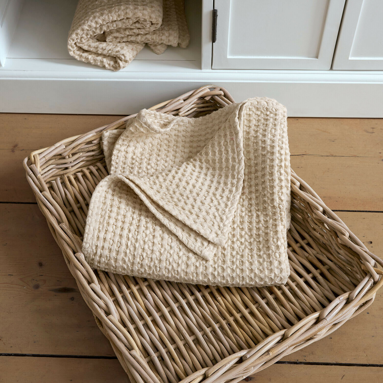 Handtuch Maralei Beige Baumwoll-Waffeldecke in einem Weidenkorb auf hellem Holzboden