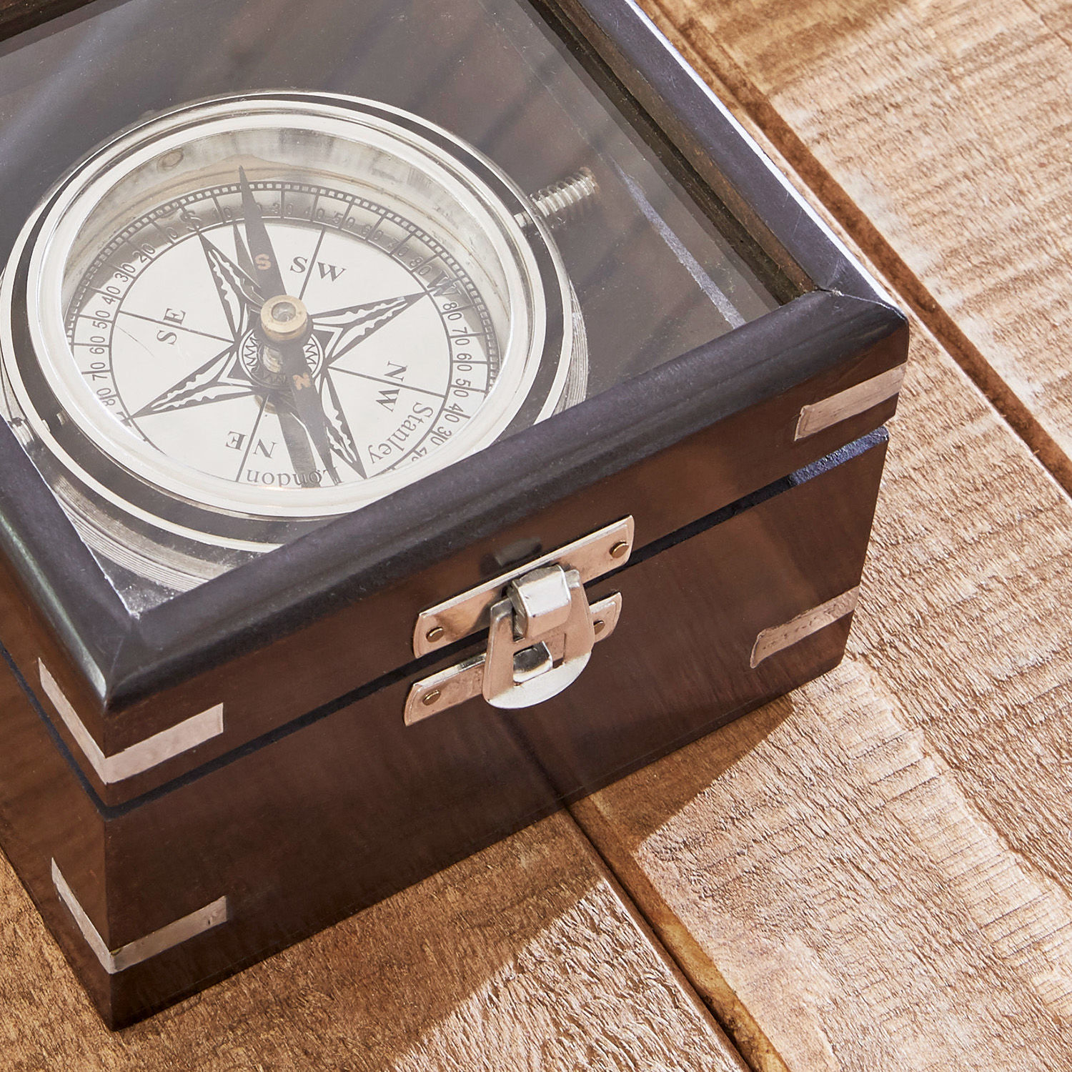 Holzbox mit Kompass unter Glasdeckel, dekoratives Accessoire auf Holztisch