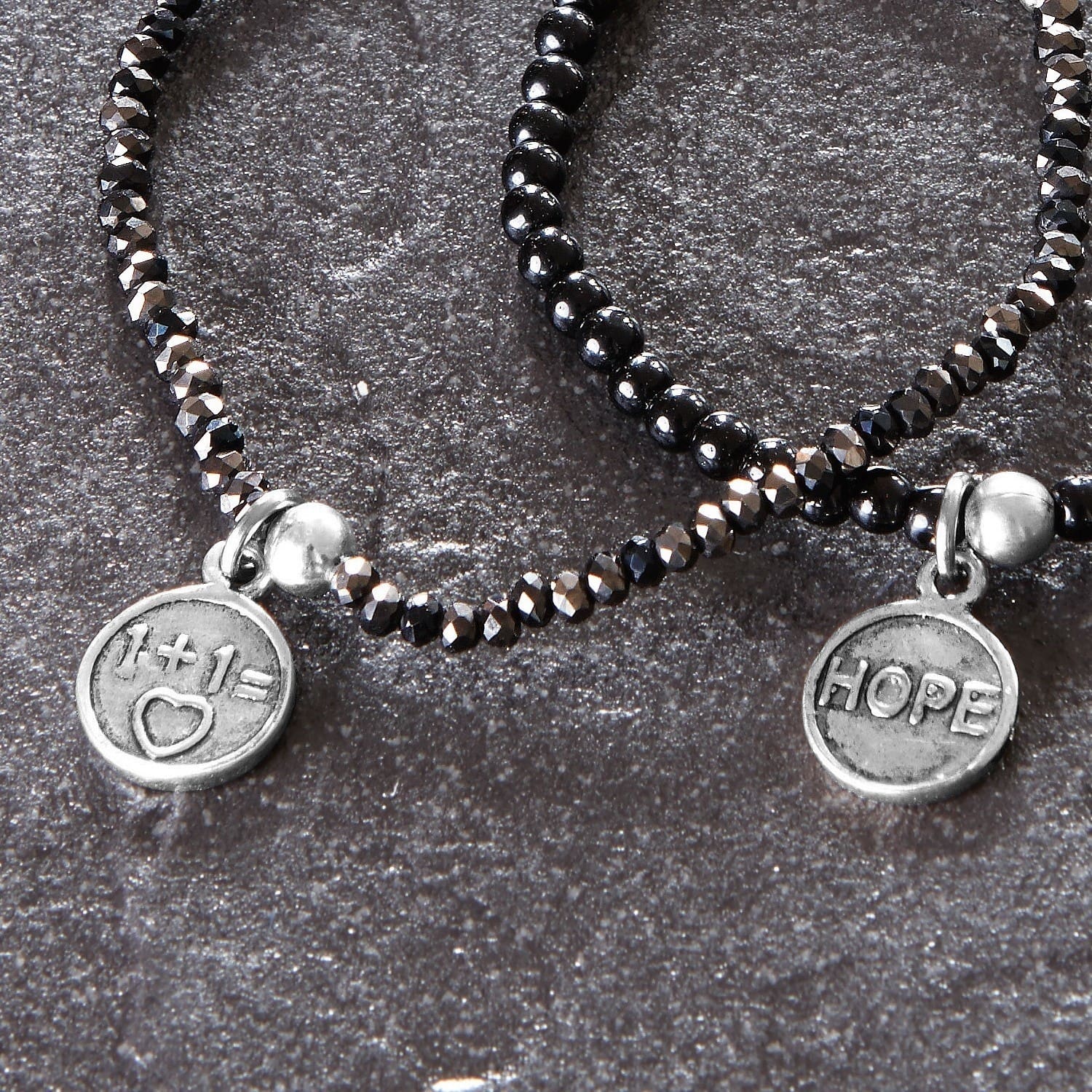 Armbänder aus schwarzen Perlen mit Metallanhängern mit HOPE-Schriftzug und Herzsymbol