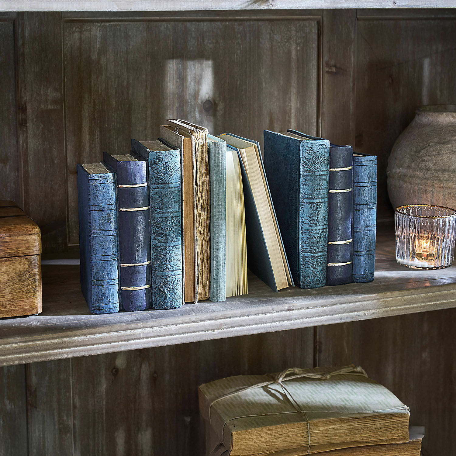 Buchstütze 2er Set Morvini Alte Bücher mit blauen und beigen Einbänden auf einem Holzregal neben einem Windlicht