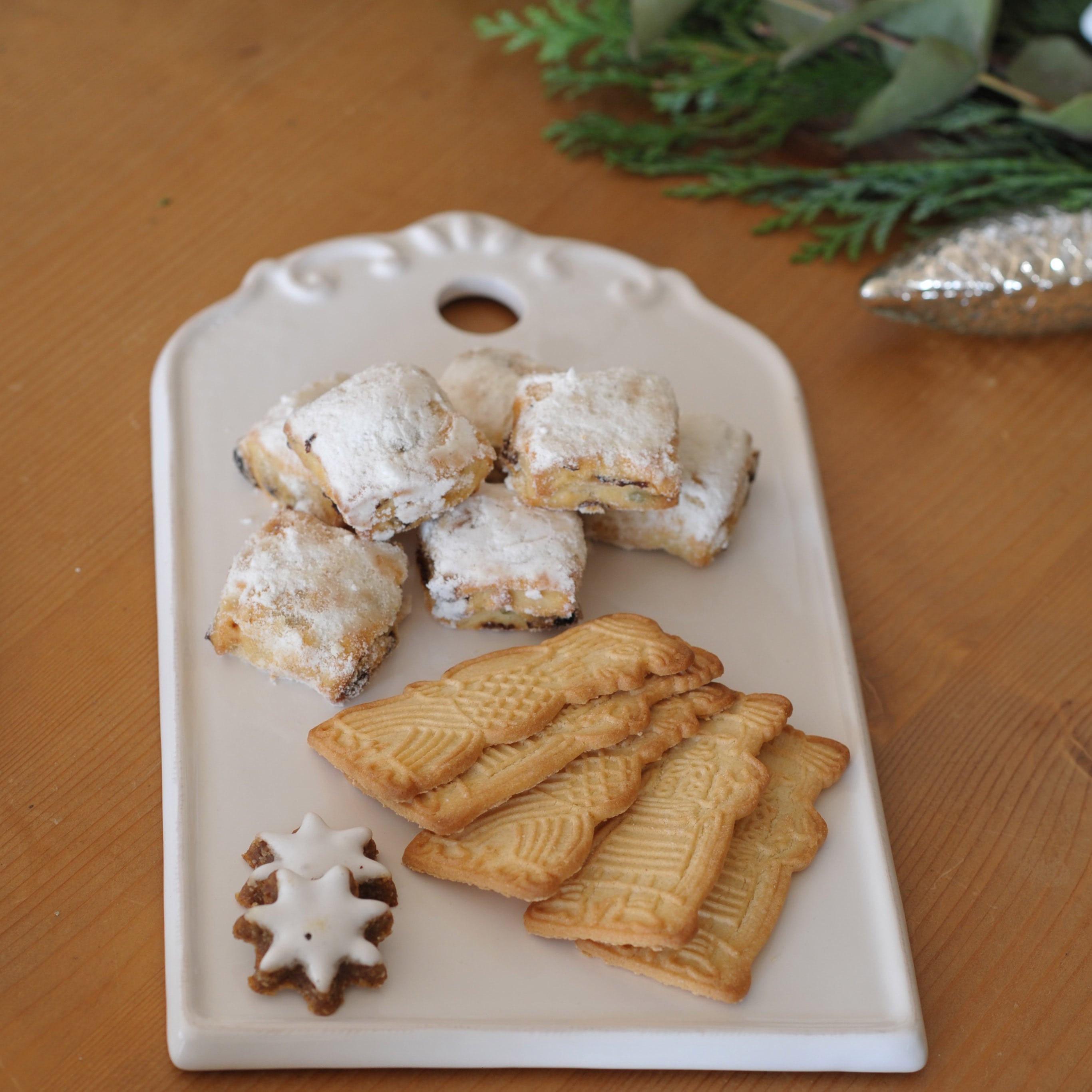 Weißes Keramiktablett mit traditionellen Weihnachtsplätzchen auf Holztisch