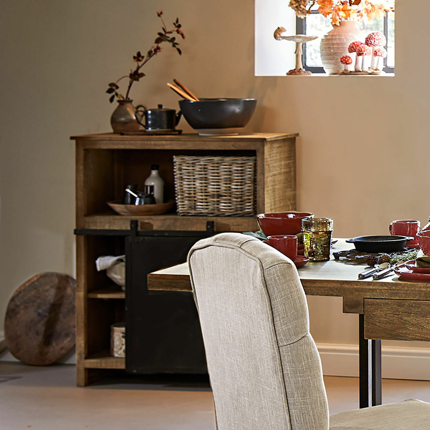 Esszimmer mit Holztisch, beige gepolstertem Stuhl und rustikalem Sideboard mit Korb aus Weide